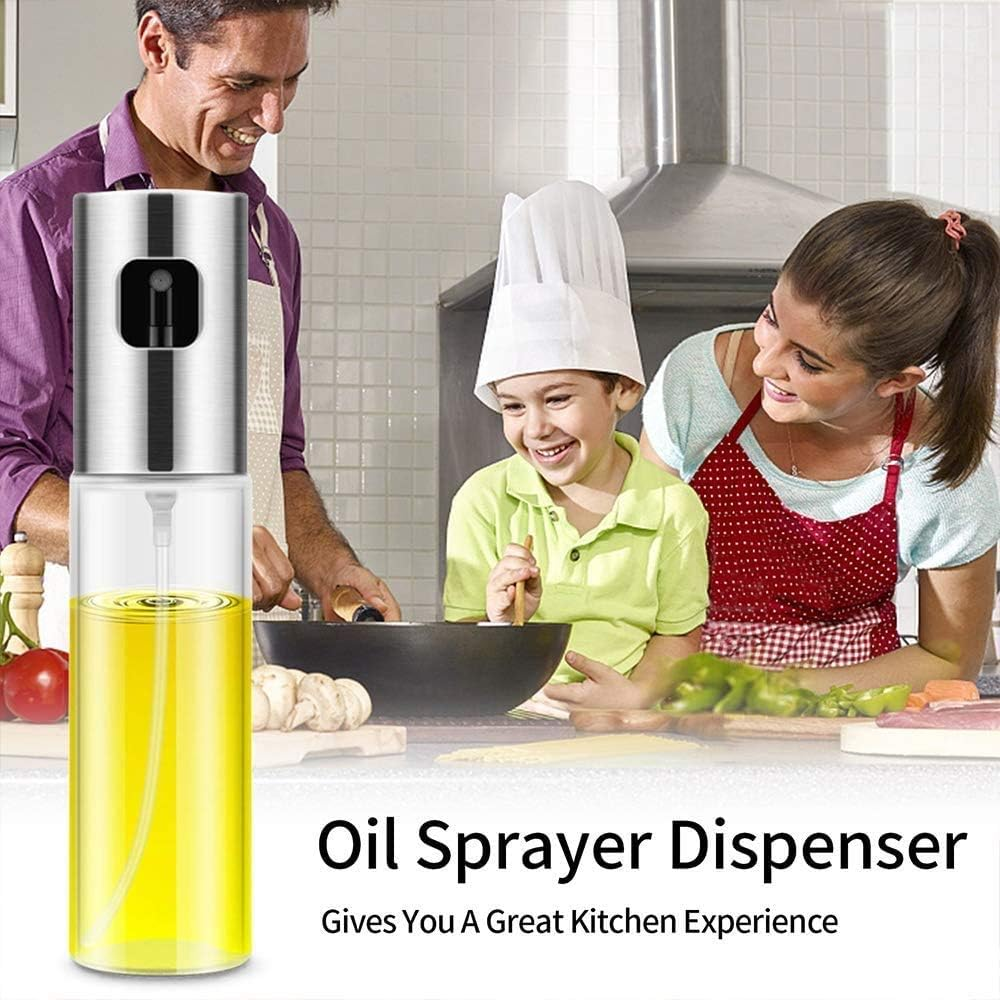 Familie kocht in der Küche. Ölsprüher im Vordergrund. Lächeln Erwachsene und Kind mit Kochmütze.