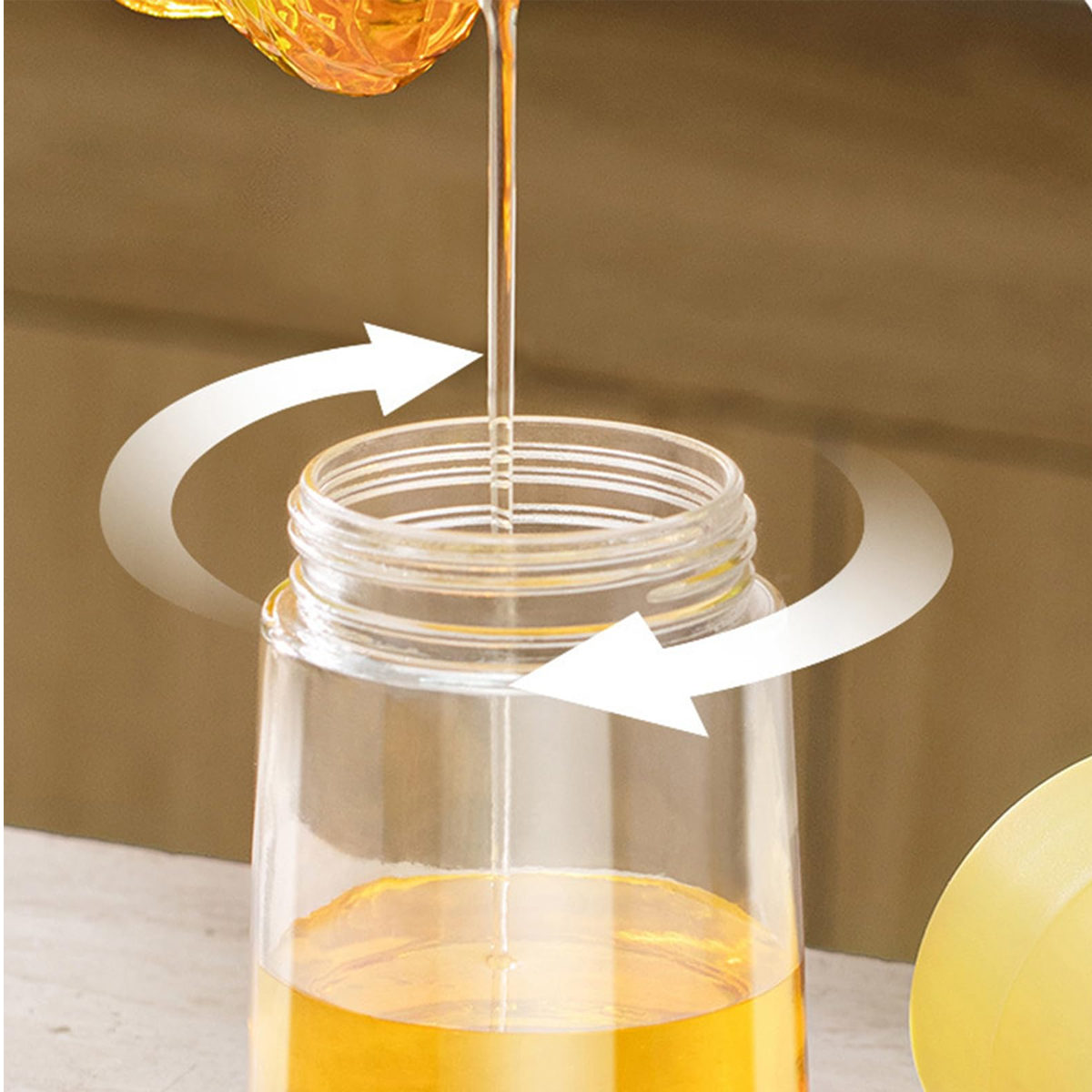 Honig gießt in ein Glas. Pfeile deuten auf eine kreisförmige Bewegung hin. Der Hintergrund ist braun.