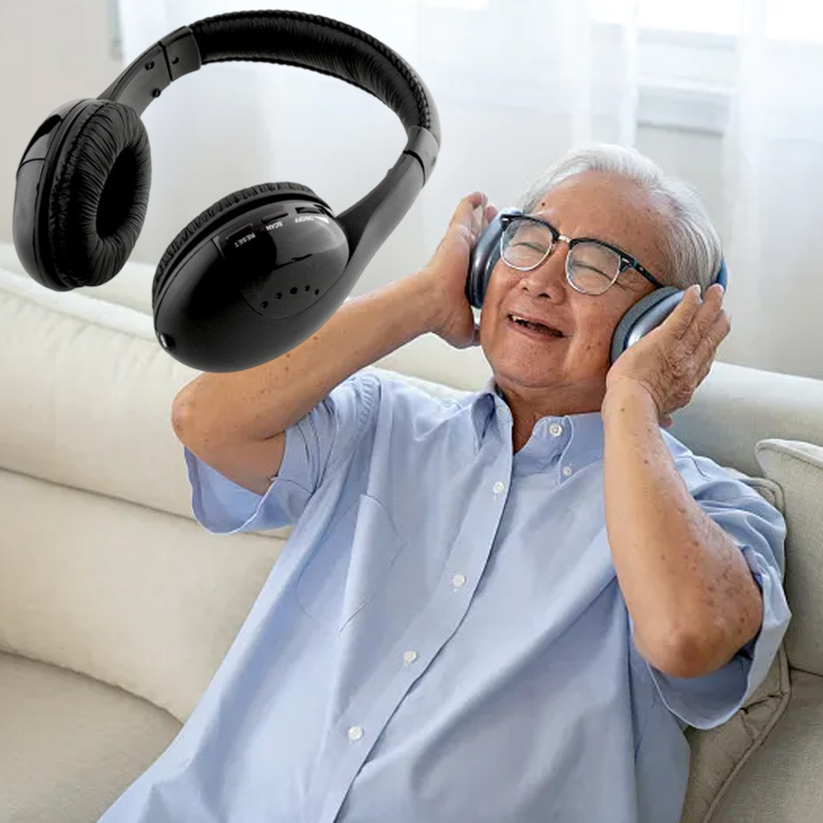 Ein älterer Mann mit Brille und blauem Hemd lächelt, während er Kopfhörer trägt. Schwarze Kopfhörer sind über ihm.