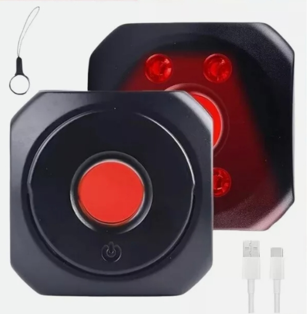 Zwei schwarze, achteckige Geräte mit roten Lichtern. Eines hat einen roten Knopf und ein Energiesymbol. Weiße USB-Kabel und ein Schlüsselband sind sichtbar.
