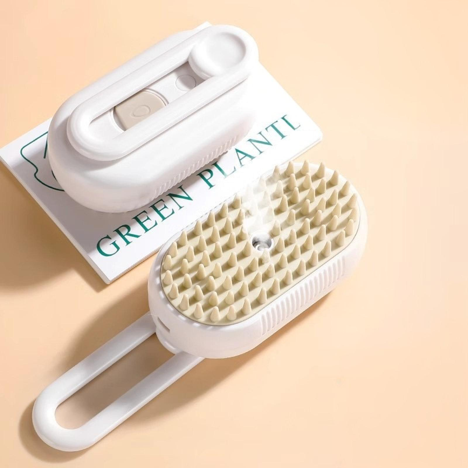 Weißer Kopfhautmassager mit beigefarbenen Borsten neben einem zusammengeklappten Gerät auf Papier.