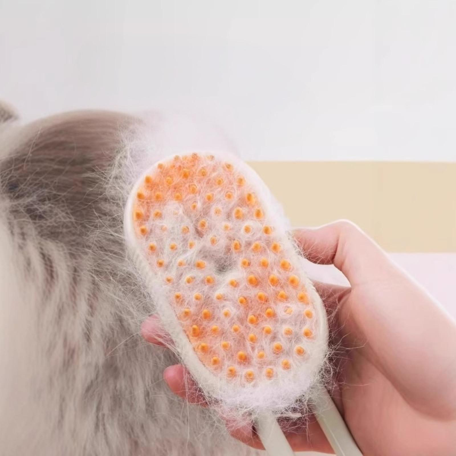 Eine Hand hält eine Haustierbürste und entfernt Fell von einem grauen Tier. Die Bürste hat orangefarbene Spitzen und einen weißen Griff.