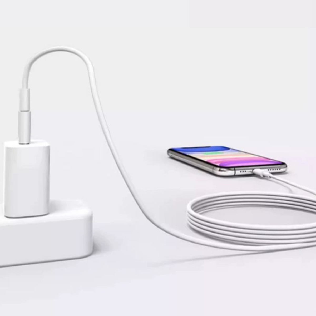 Ein weißes Telefonladegerät ist an eine weiße Steckdose angeschlossen. Ein Telefon liegt auf der Oberfläche und ist durch ein weißes Kabel verbunden.