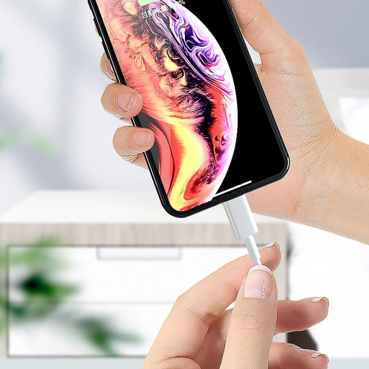 Eine Hand hält ein Telefon mit farbenfrohem Display. Die andere Hand verbindet ein weißes Ladekabel mit dem Telefon.