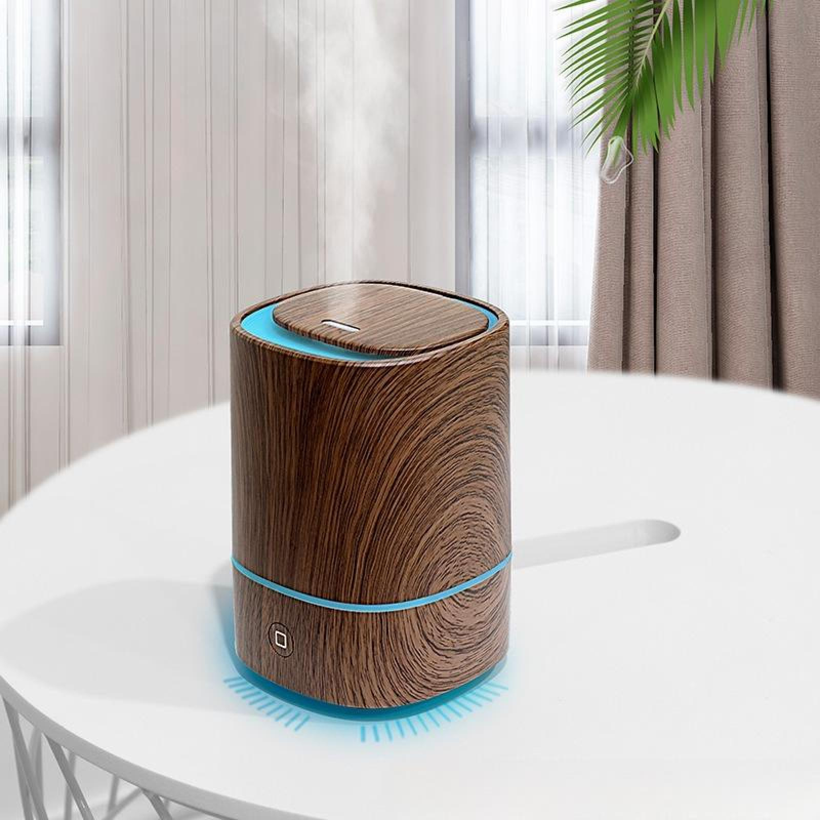 Ein Holzmaserungs-Luftbefeuchter mit blauen Akzenten steht auf einem weißen Tisch. Dampf steigt auf, in der Nähe eines Fensters.