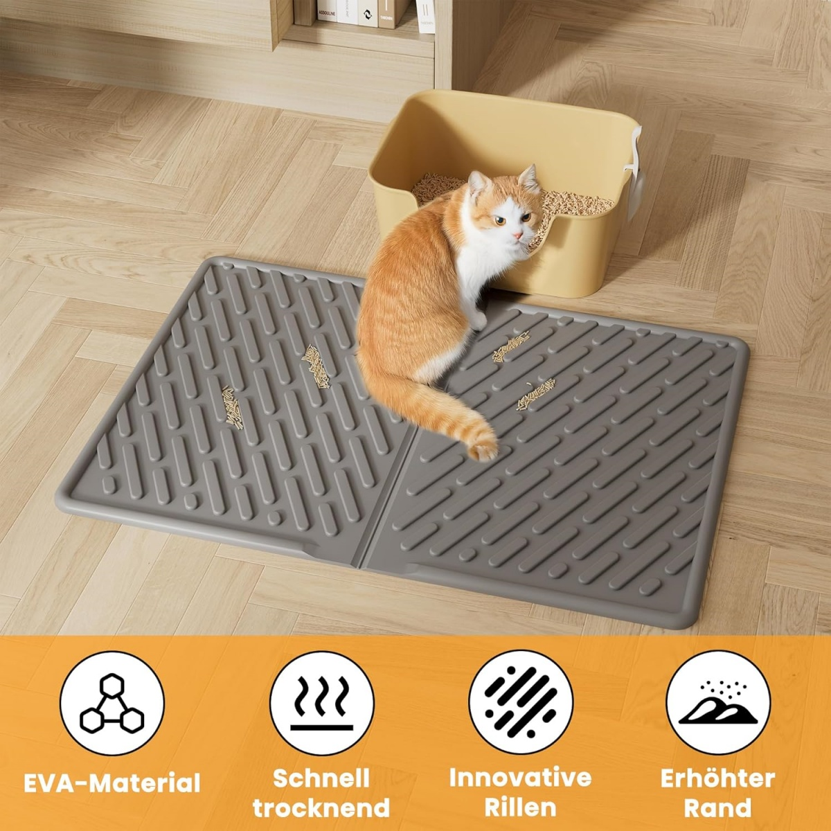 Eine orange-weiße Katze sitzt in der Nähe einer beigefarbenen Katzentoilette. Darunter liegt eine graue Matte. Streu liegt auf der Matte.