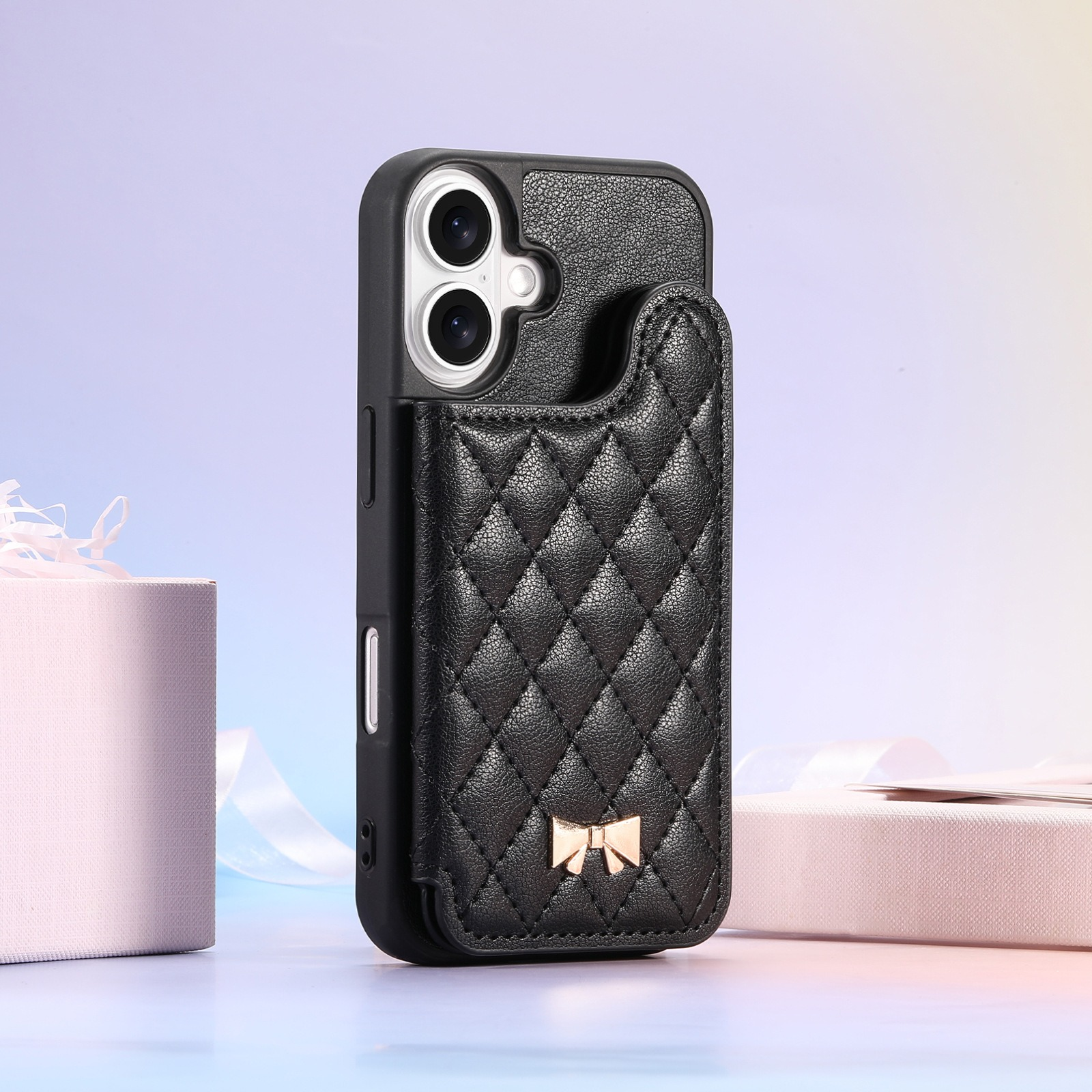 Custodia per telefono nera con design trapuntato e fiocco dorato. Contiene il telefono. Regali rosa e bianchi sullo sfondo.