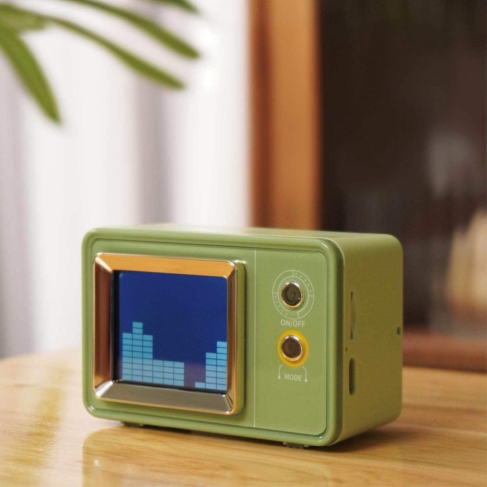 Ein grünes Retro-Radio mit einem Bildschirm, der Schallwellen anzeigt, auf einer Holzoberfläche. Bedienelemente sind sichtbar.