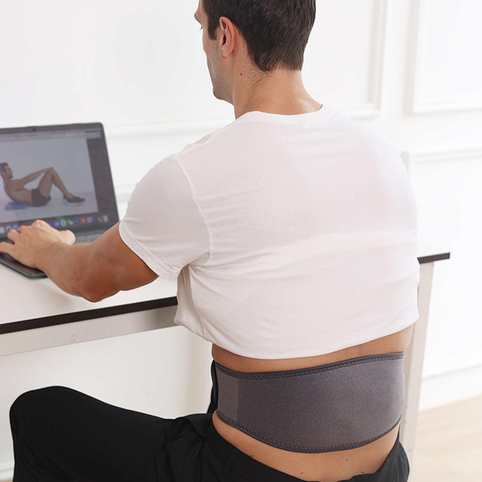 Mann mit Rückenstütze, sitzt und schaut sich ein Laptop-Video an. Weißes Hemd, schwarze Hose. Graue Klammer.