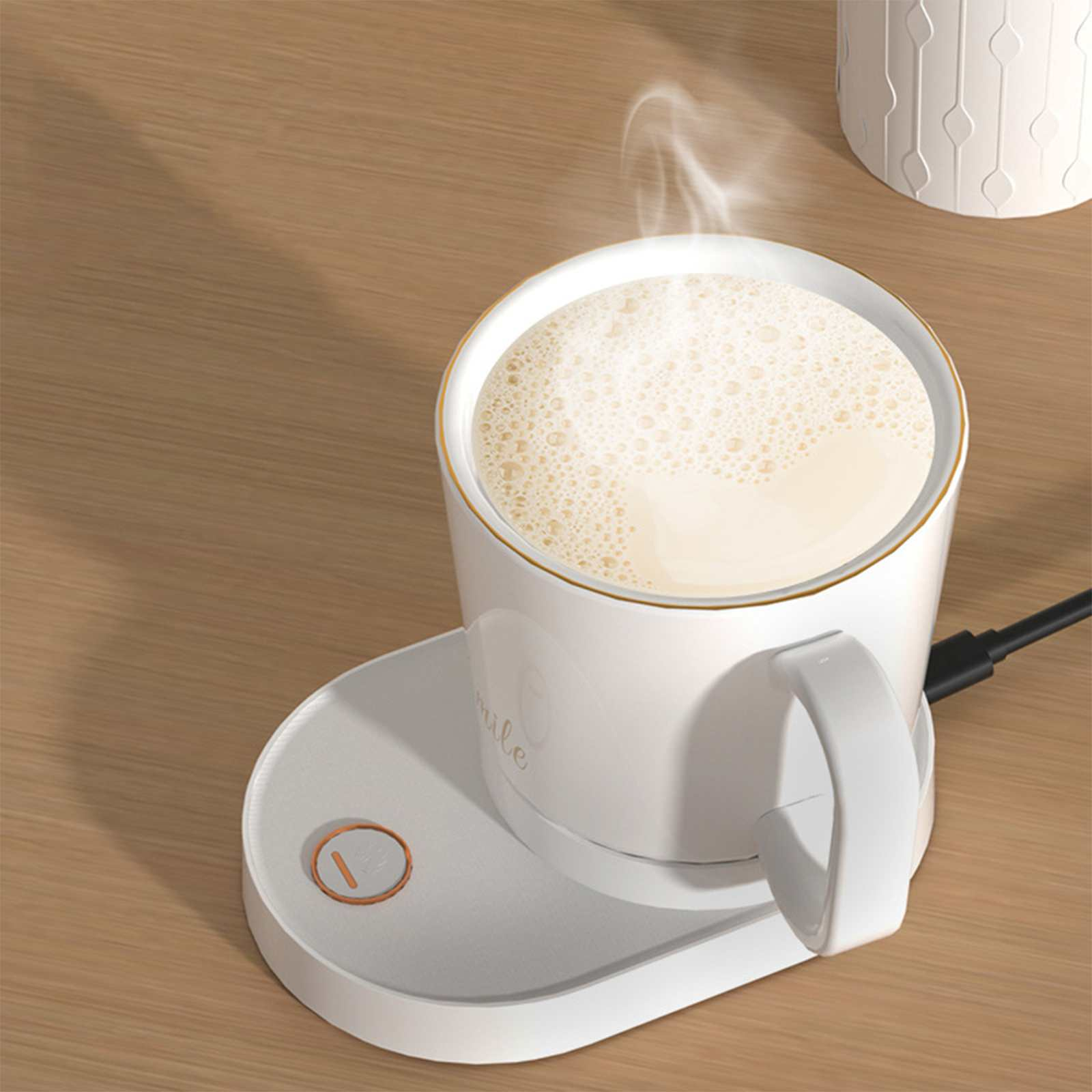 Weiße Tasse mit Kaffee auf einem Wärmer. Dampf steigt aus der Tasse auf. Der Wärmer hat einen orangefarbenen Knopf. Holztisch.