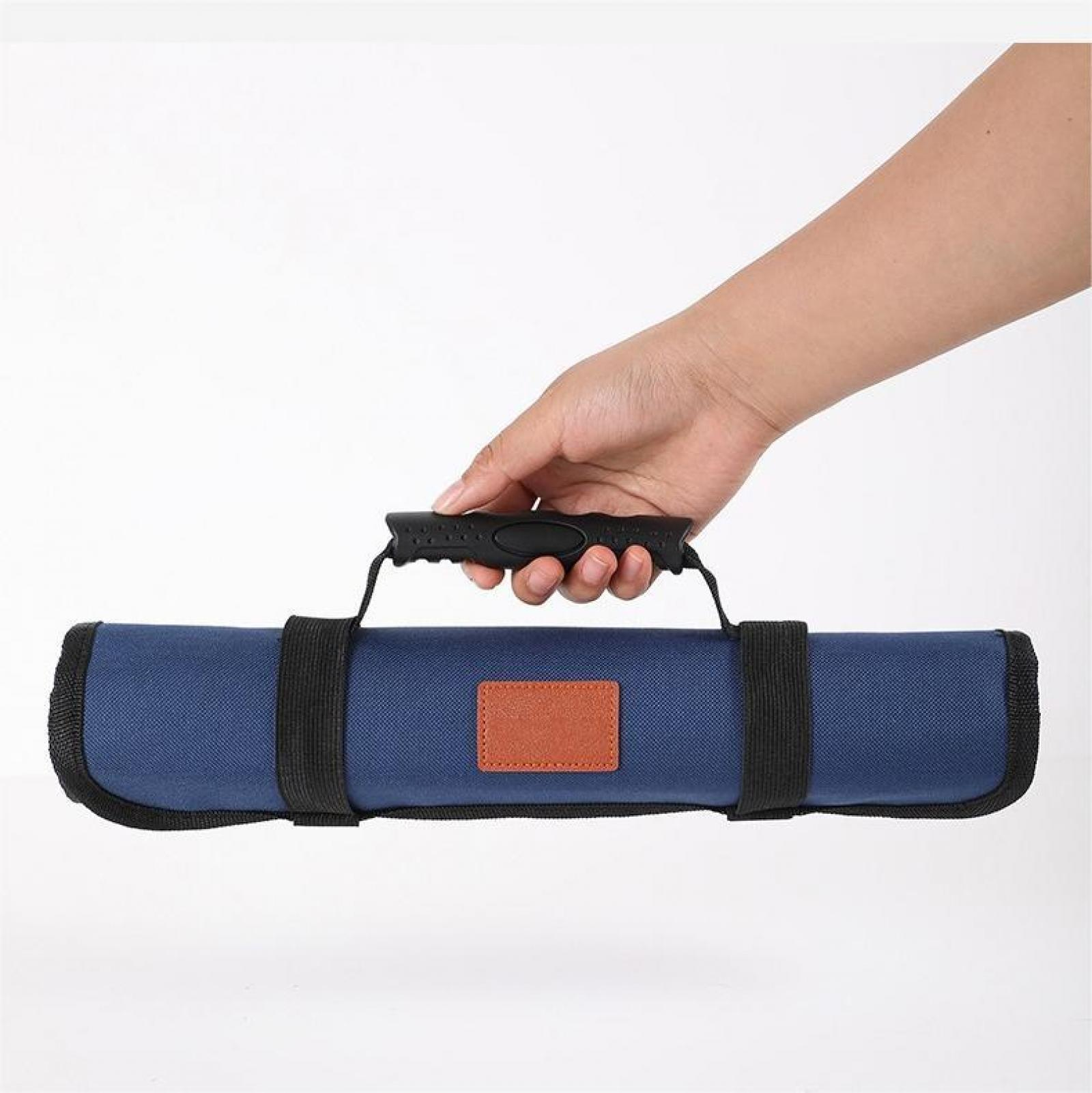 Eine Hand hält eine blaue Messertasche mit schwarzem Griff, schwarzen Riemen und einem braunen Lederaufnäher.