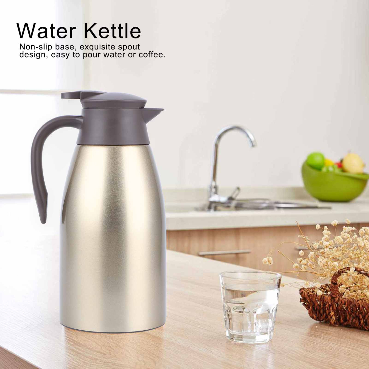 Eine metallische Wasserkanne mit dunklem grauem Deckel und Griff, ein Glas Wasser und ein Blumenkorb auf einem Holztisch.