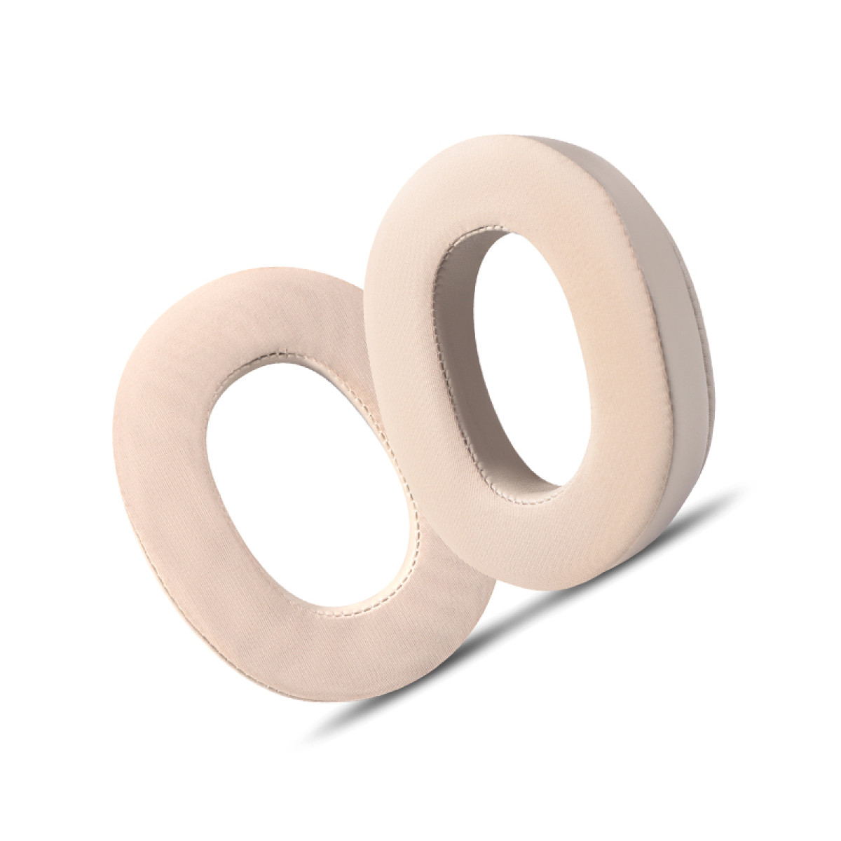 Due cuscinetti auricolari beige a forma ovale sono angolati su una superficie bianca. Hanno un aspetto morbido e imbottito.