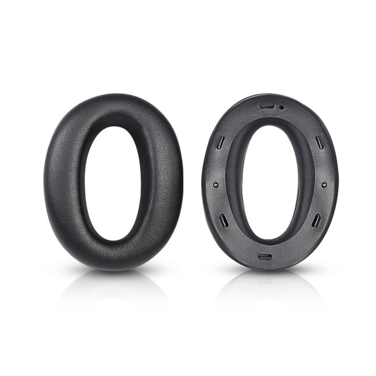 Zwei schwarze, oval geformte Kopfhörer-Ohrpolster. Eines ist ein solides Kissen, das andere hat kleine Löcher und Details am Rand.