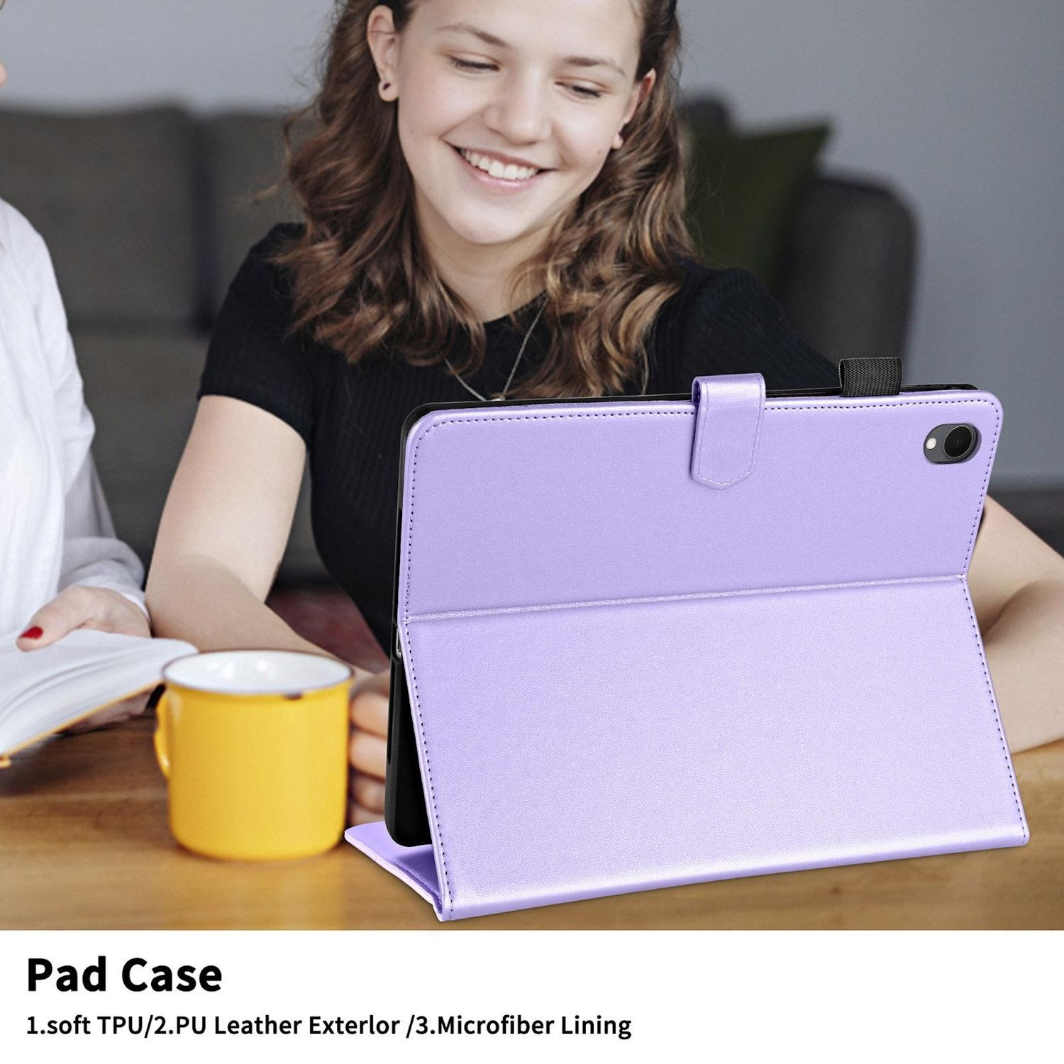 Eine lächelnde junge Frau hält ein Tablet mit einer lila Hülle. Auf einem Tisch steht eine gelbe Tasse. Der Hintergrund ist unscharf.