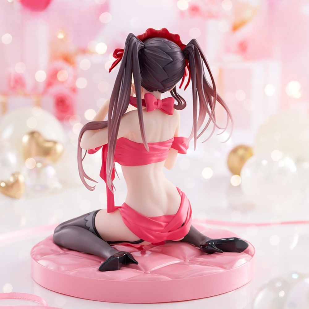 Una statuetta di una donna in abito rosa, inginocchiata su un cuscino rosa. Lo sfondo ha palloncini e luci bokeh.