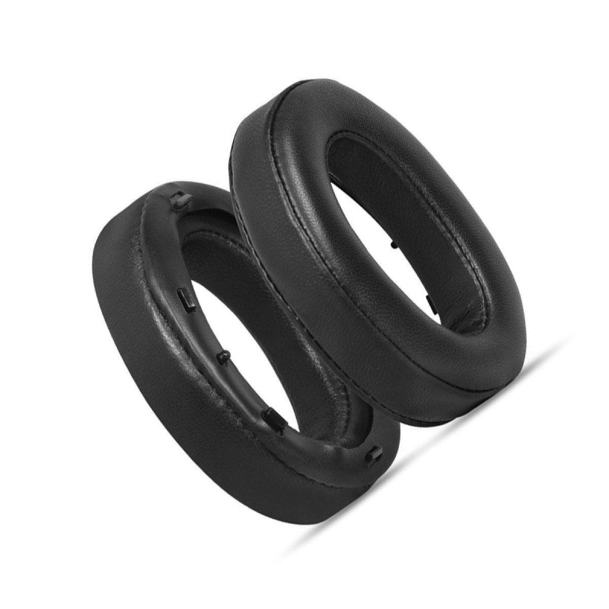 Due cuscinetti auricolari neri, di forma ovale, sono impilati. I cuscinetti sono realizzati in materiale liscio e poggiano su una superficie bianca.