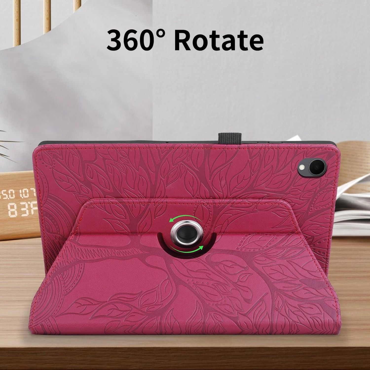 Una tableta en una funda rosa está sobre una superficie de madera. La funda tiene un patrón de hojas. Un reloj es visible al fondo.