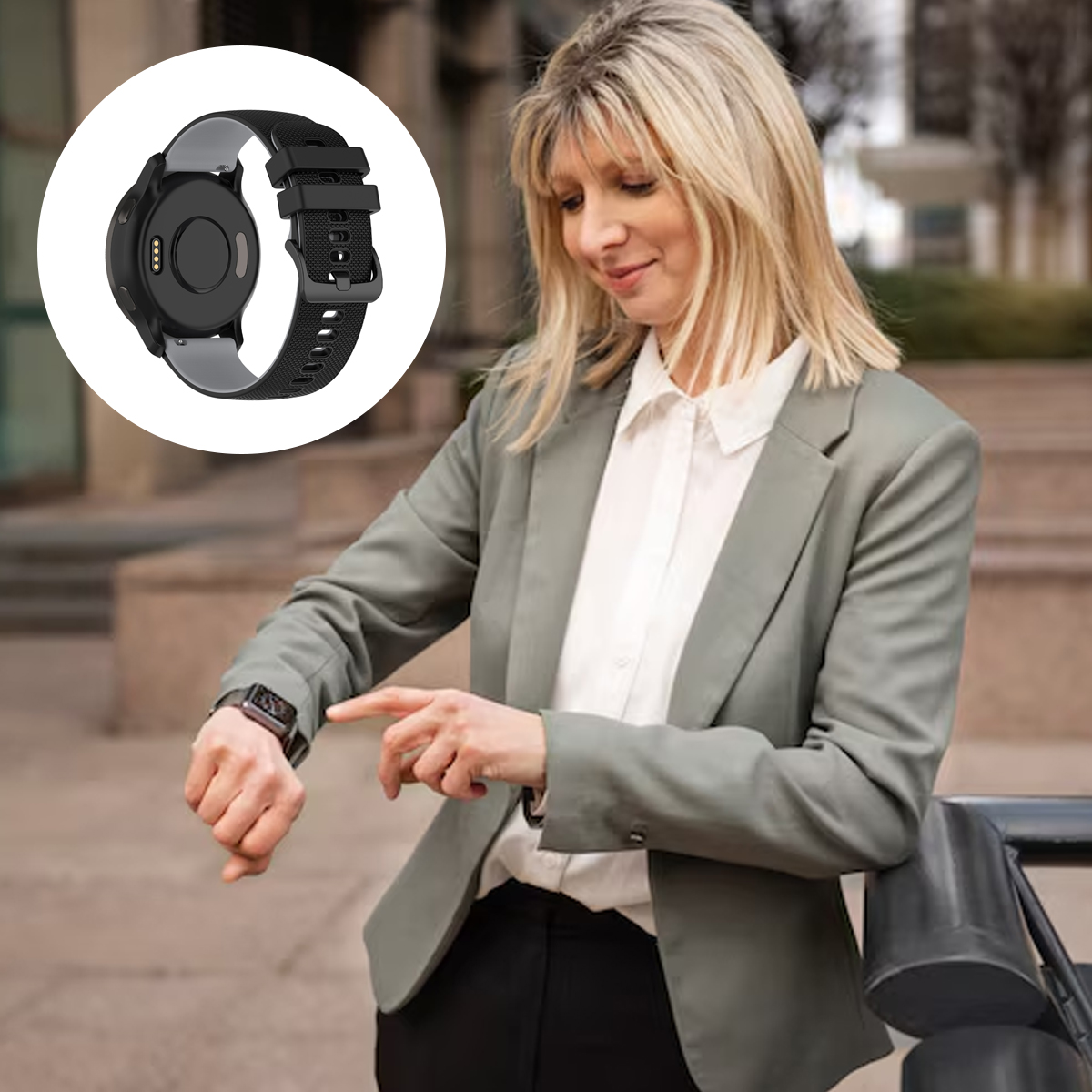 Eine Frau im Blazer schaut auf eine Smartwatch. Eine schwarze Uhr wird in der Ecke angezeigt. Sie steht draußen und lehnt an einem Geländer.