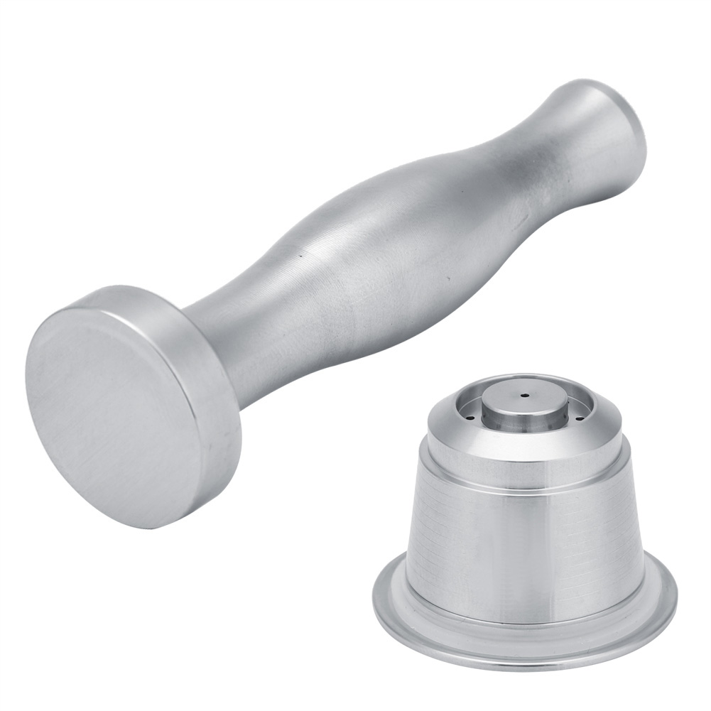 Ein Metall-Kaffee-Tamper und eine wiederverwendbare Kaffeekapsel auf weißem Hintergrund. Der Tamper hat einen Griff und eine flache, runde Basis.