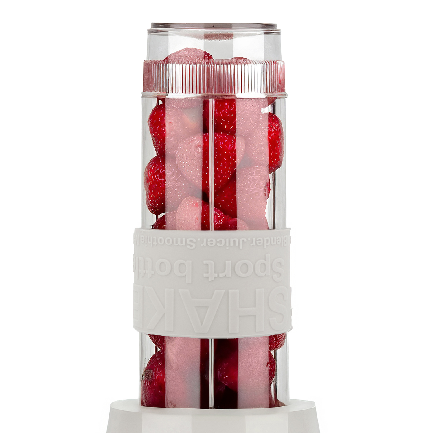 Una licuadora transparente llena de fresas rojas. Tiene una banda blanca con las palabras 'SHAKE sport bottle'. El fondo es blanco.