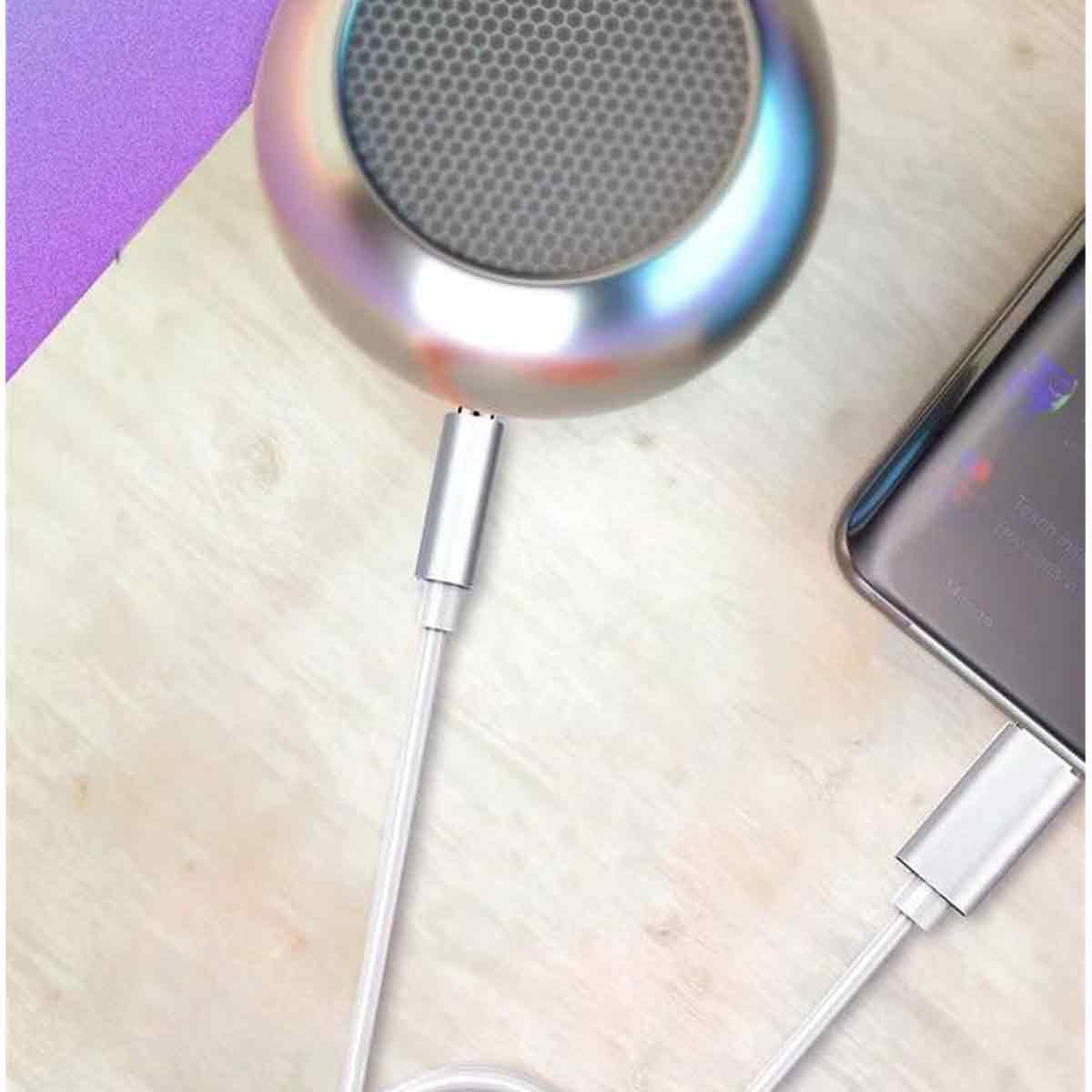 Nahaufnahme eines Lautsprechers, Kabels und Telefons. Der Lautsprecher ist über ein Kabel mit dem Telefon verbunden. Die Szene befindet sich auf einer Holzoberfläche.
