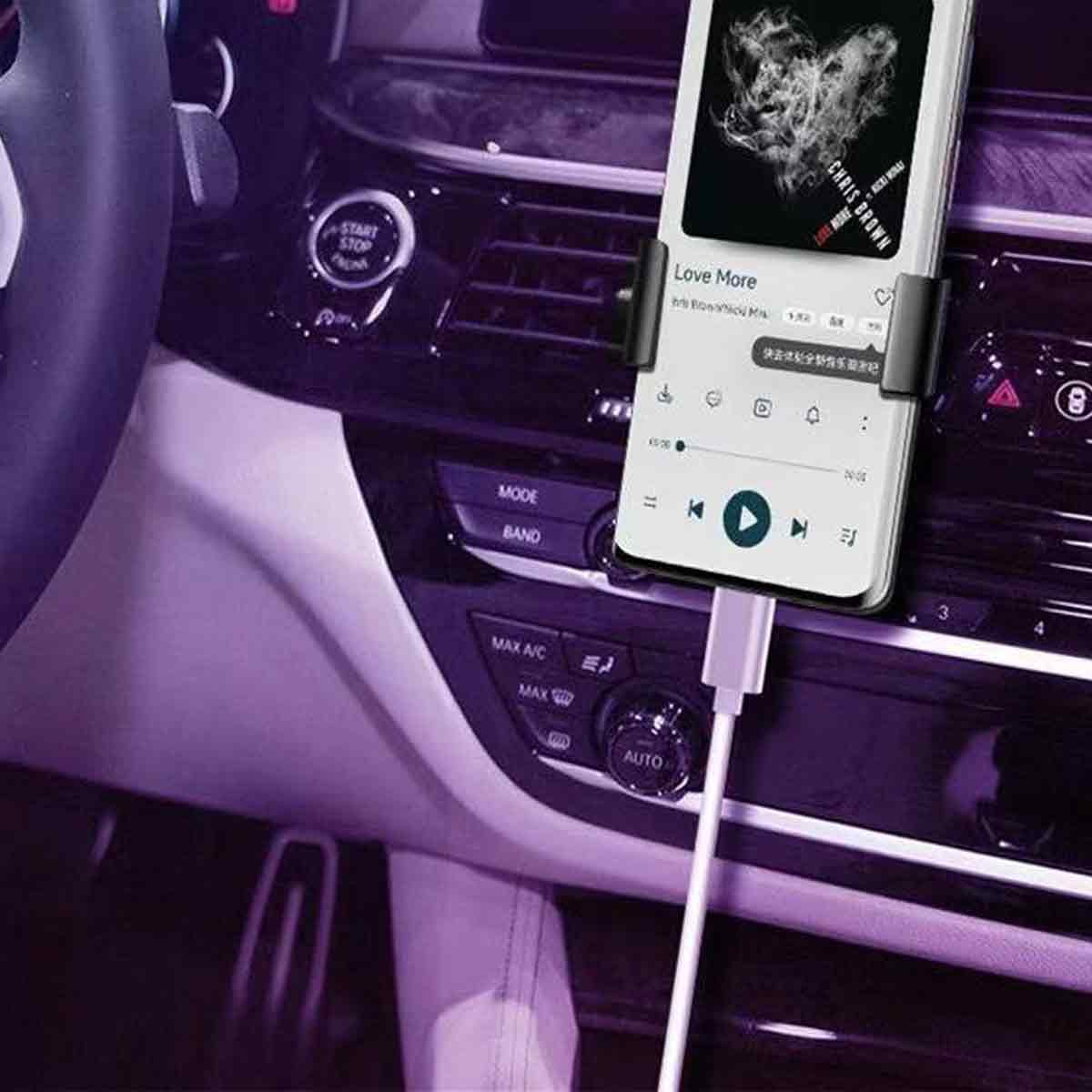 Ein Smartphone, das im Auto Musik abspielt. Der Bildschirm zeigt den Song 'Love More' von Chris Brown. Das Auto ist lila.