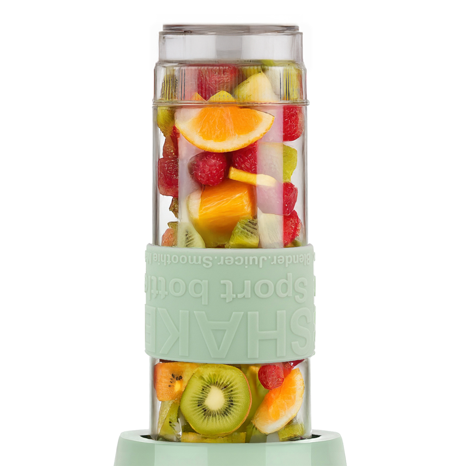 Una licuadora transparente llena de frutas cortadas: rodajas de naranja, kiwi, frambuesas. La licuadora es verde menta con la palabra SHAKE.