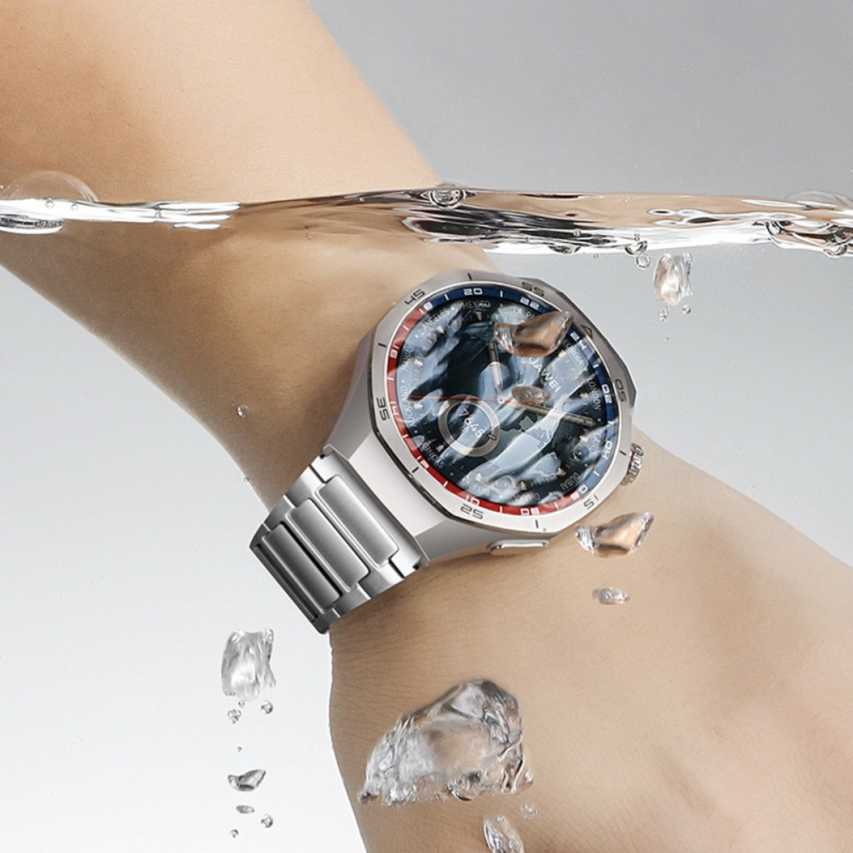 Eine silberne Smartwatch ist in Wasser getaucht und zeigt die Uhrzeit an. Wassertropfen und Blasen umgeben die Uhr und das Handgelenk. Der Hintergrund ist weiß.