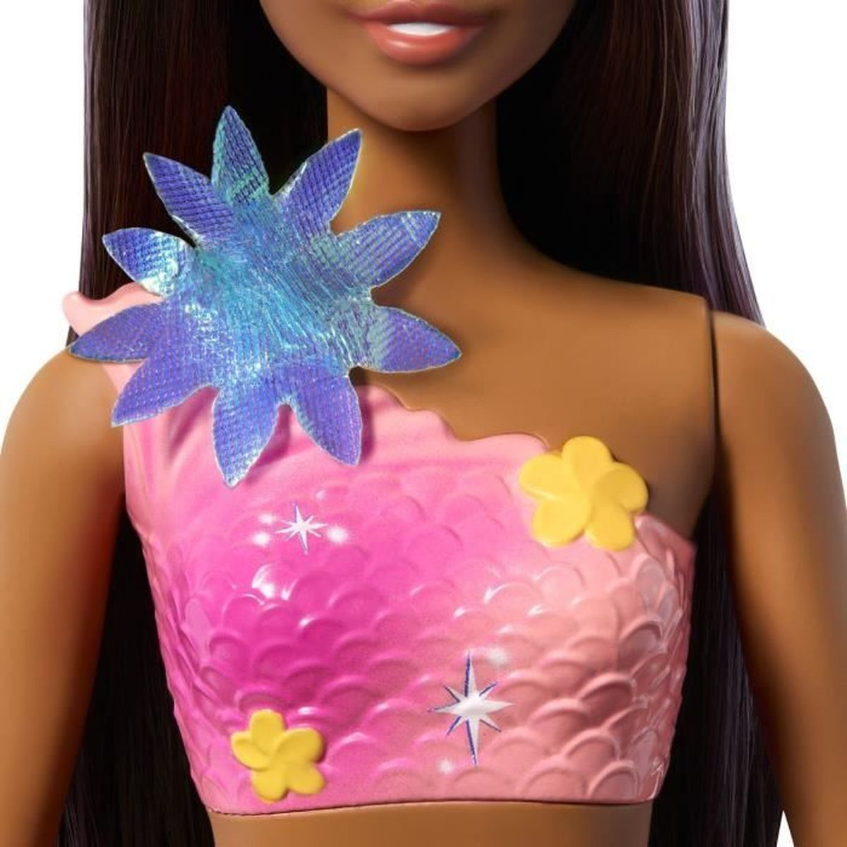 Nahaufnahme einer Puppe. Pinkes Oberteil mit gelben Blumen und einem blauen Stern. Dunkle Haare und Haut. Teil eines Meerjungfrauen-Outfits.