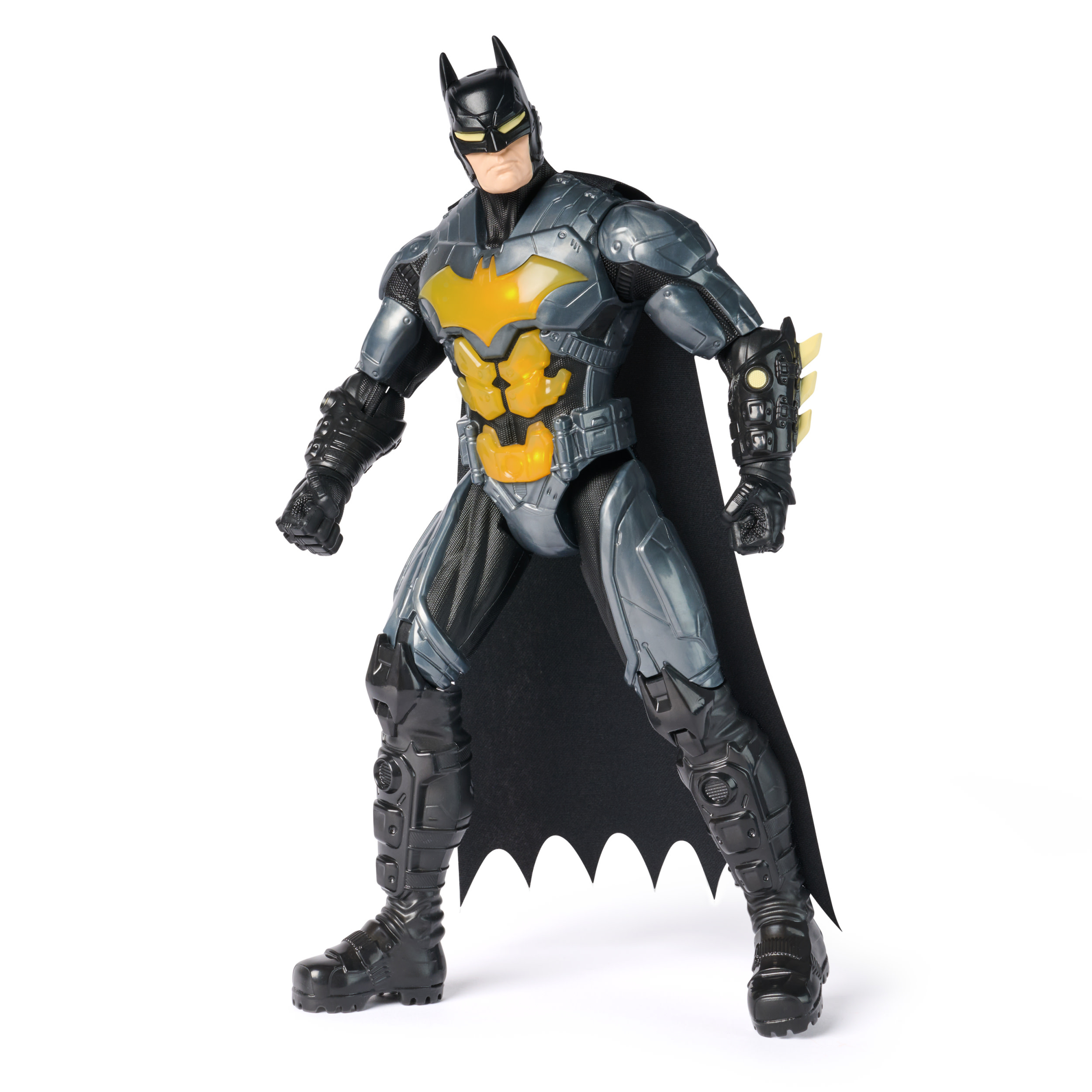 Eine Batman-Actionfigur steht da. Sie hat einen schwarzen Umhang, graue Rüstung mit gelbem Brustemblem und eine schwarze Kapuze.