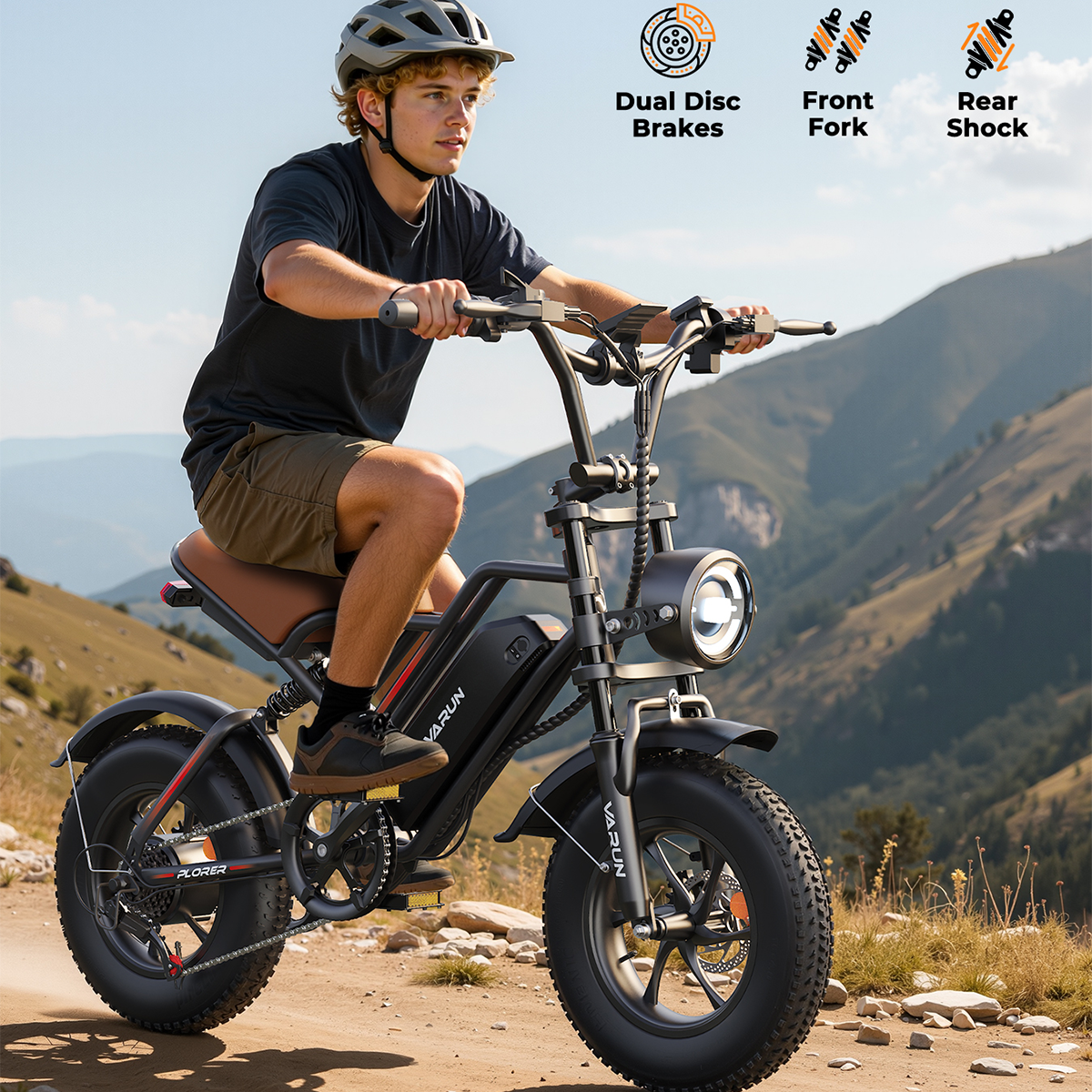 Mężczyzna na czarnym rowerze elektrycznym jedzie po polnej ścieżce. Rower ma reflektor i duże opony. W tle widać góry i niebo.