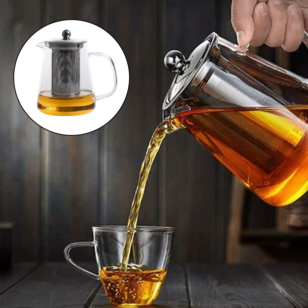 Tee wird aus einer Glasteekanne in eine Glastasse gegossen. Die Teekanne hat einen Metall-Teeeinsatz. Holztisch im Hintergrund.
