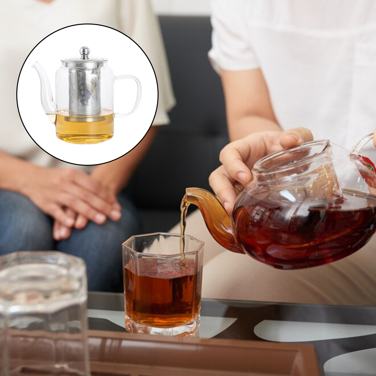 Eine Person gießt Tee aus einer Glaskanne in ein Glas. Eine Teekanne mit Tee und ein Glas mit Tee stehen auf dem Tisch.