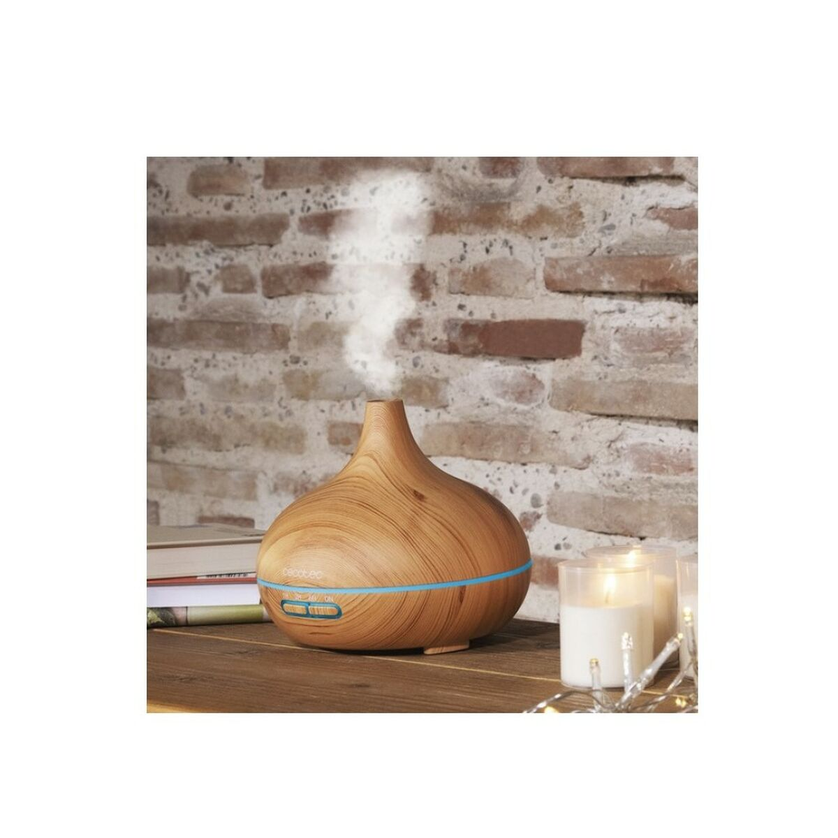 Un diffusore di aromi in legno rilascia vapore, posto su un tavolo di legno. Candele e un muro di mattoni sullo sfondo.