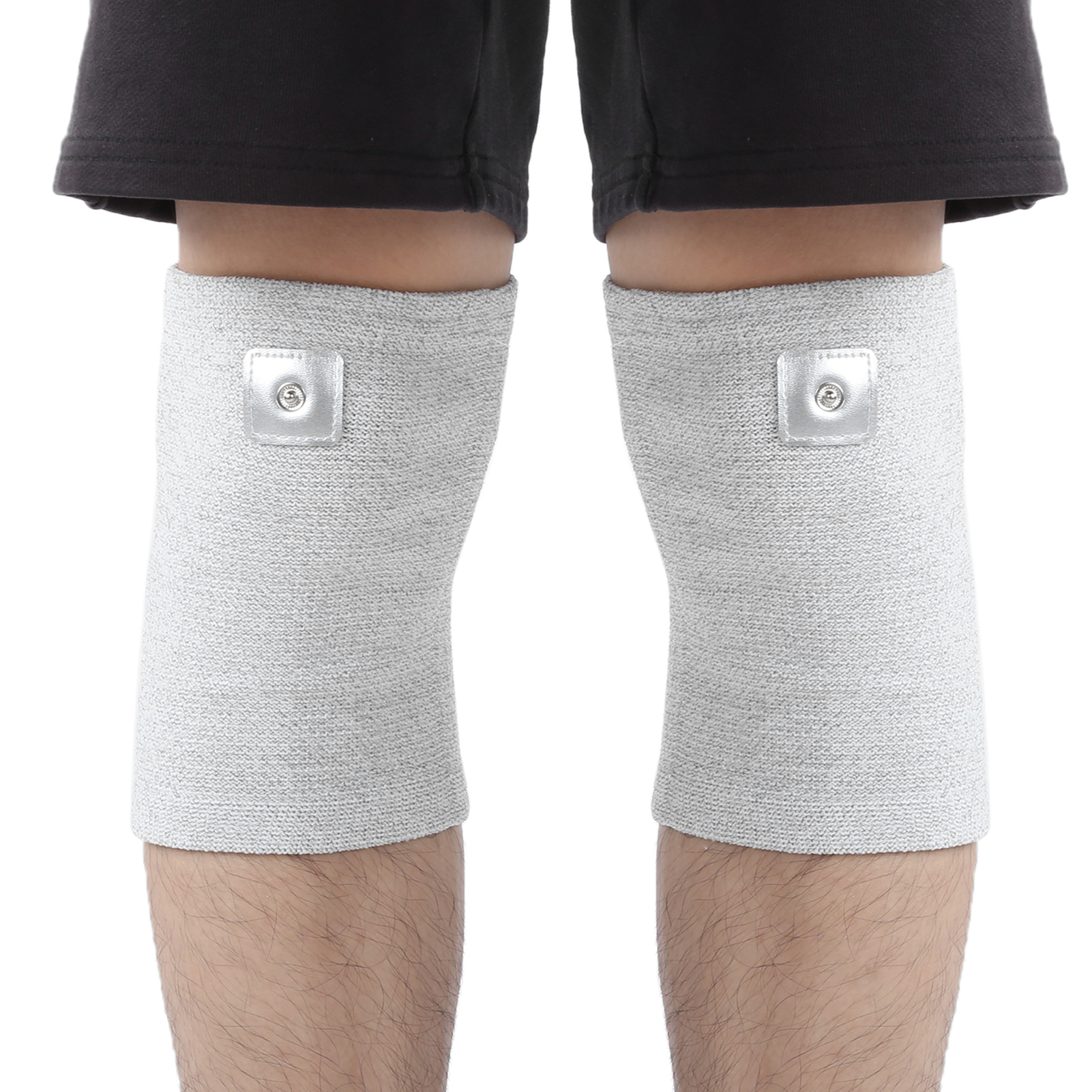 Beine einer Person mit grauen Knieorthesen und metallischen quadratischen Aufnähern. Schwarze Shorts sind sichtbar.