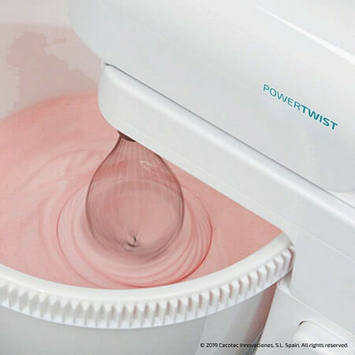 Una batidora Powertwist blanca mezcla masa rosa en un bol blanco. El batidor está en movimiento, creando remolinos en la mezcla.