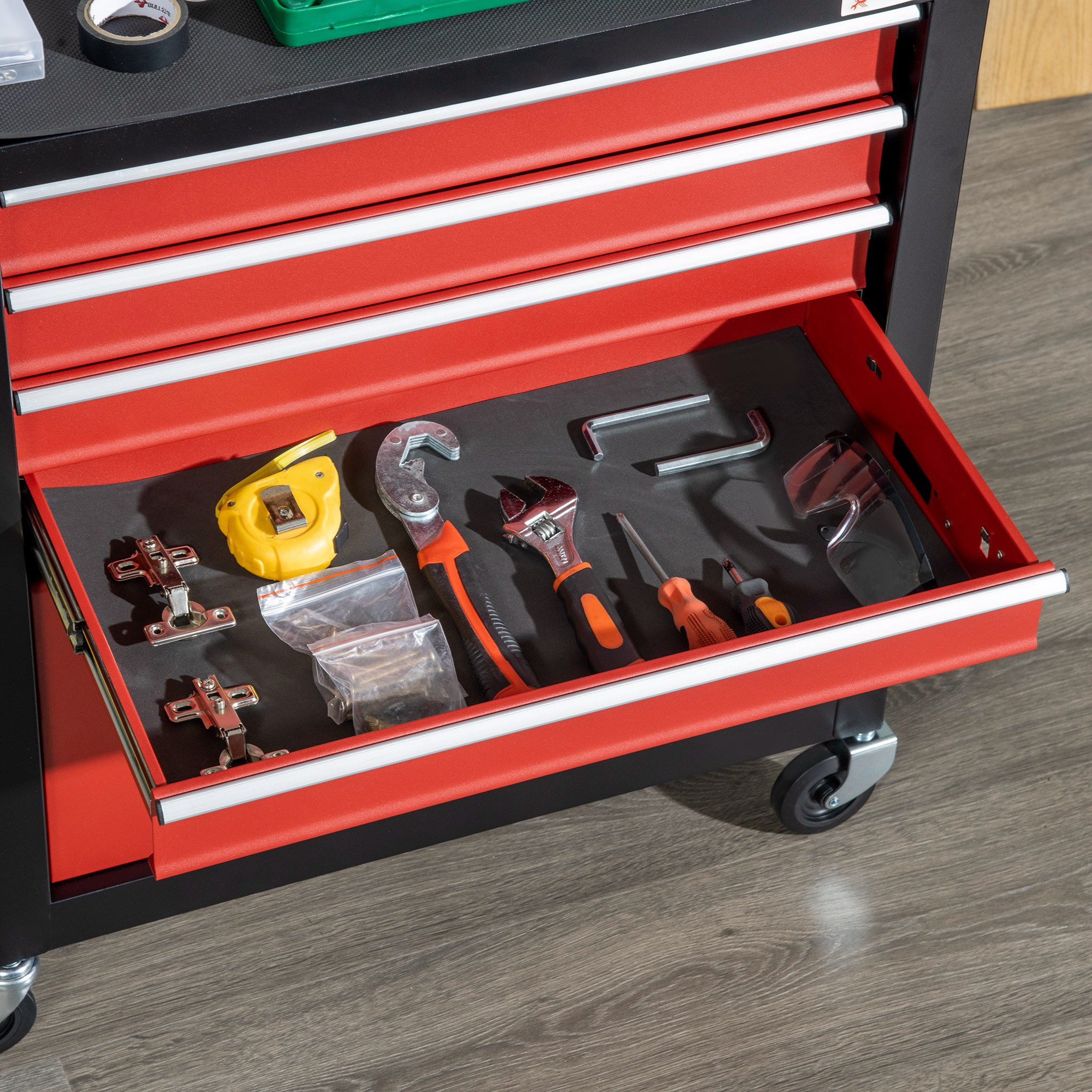 Cajón rojo de caja de herramientas abierto con herramientas como cinta métrica, llaves, destornilladores y bisagras.