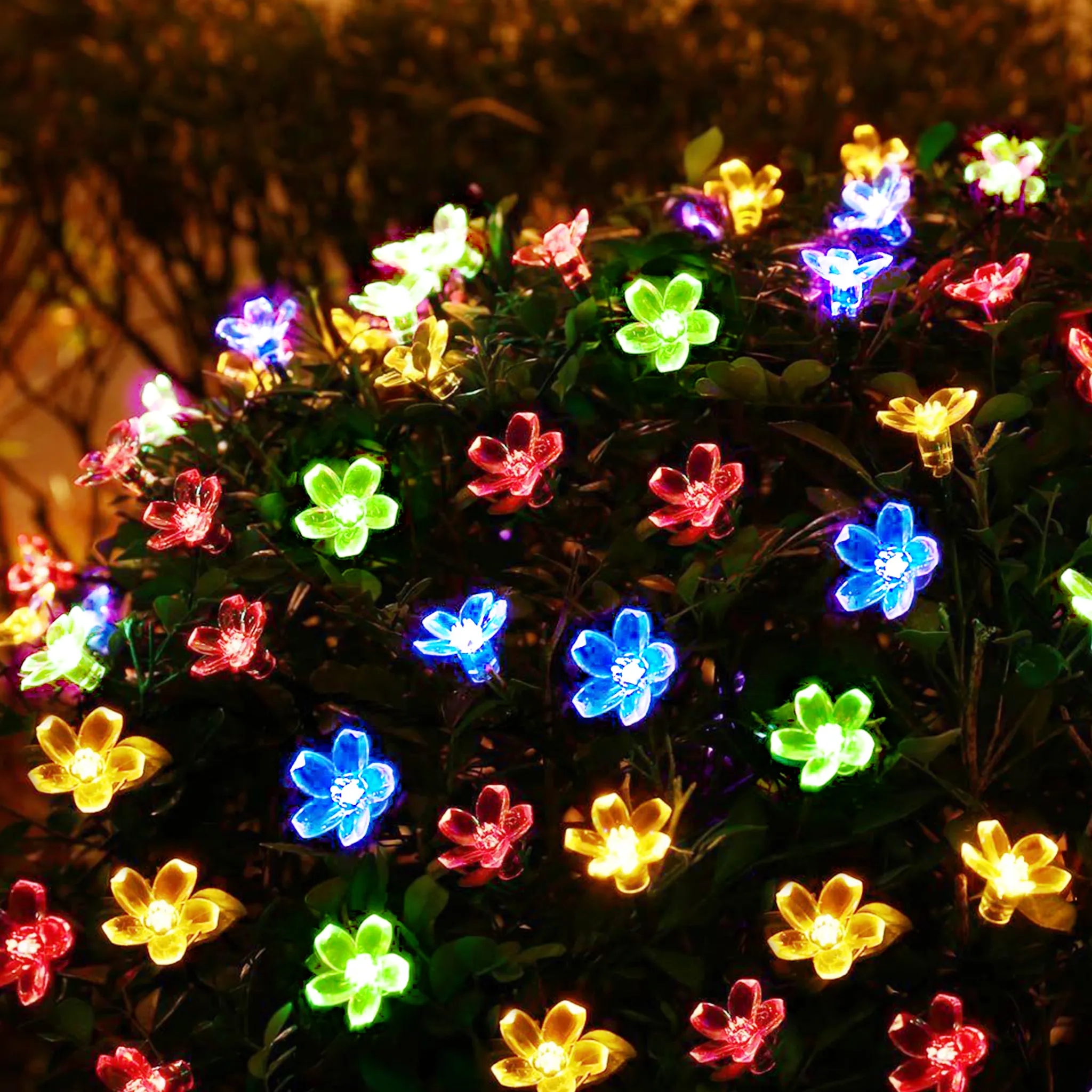 Nahaufnahme eines Busches mit zahlreichen leuchtenden Blumenlichtern in verschiedenen Farben: Rot, Blau, Grün und Gelb.