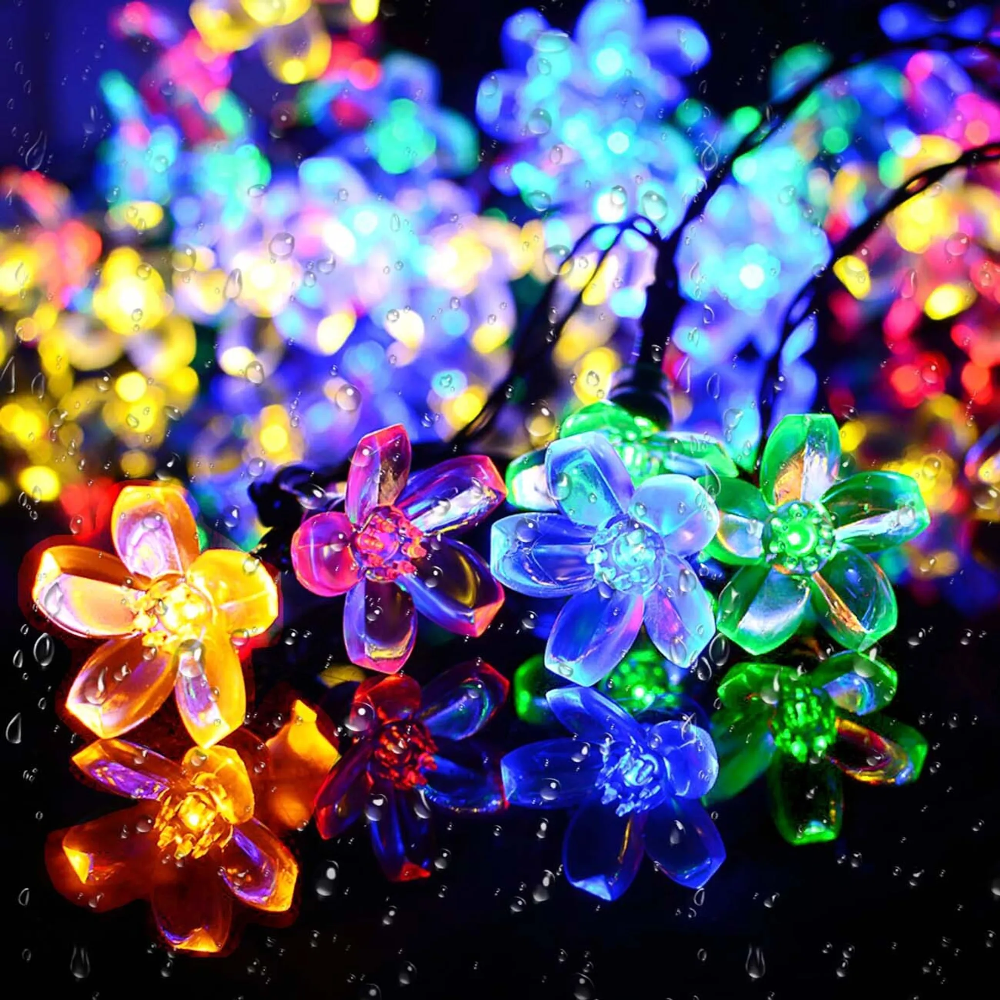 Nahaufnahme von bunten Blumenlichtern. Wassertropfen auf der Oberfläche. Hintergrund zeigt verschwommene Lichter. Die Farben umfassen Gelb, Blau und Grün.