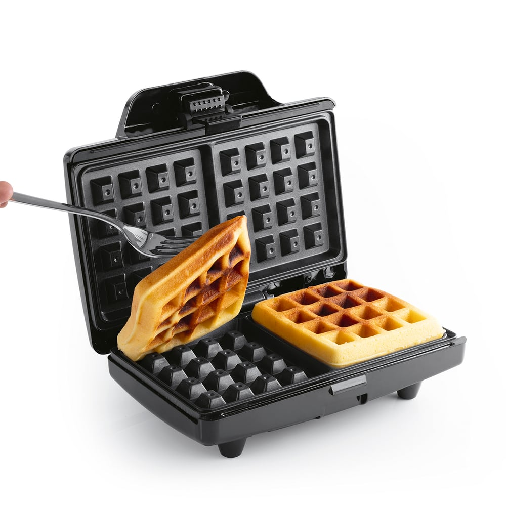Ein offenes Waffeleisen mit zwei goldbraunen Waffeln. Eine Gabel hebt eine Waffel an. Das Eisen ist schwarz.