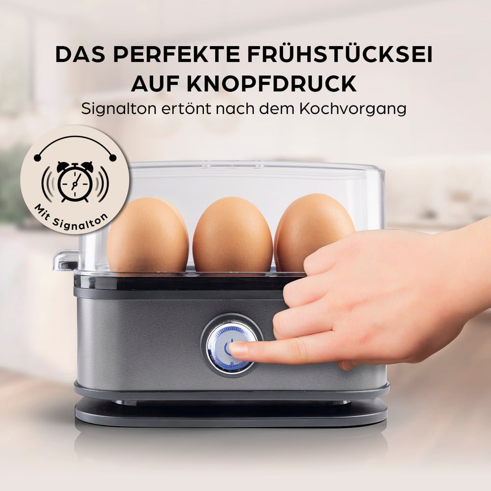Eine Hand drückt die Taste eines Eierkochers. Drei Eier liegen darin. Der Text oben lautet: 'Perfektes Frühstücksei auf Knopfdruck'.