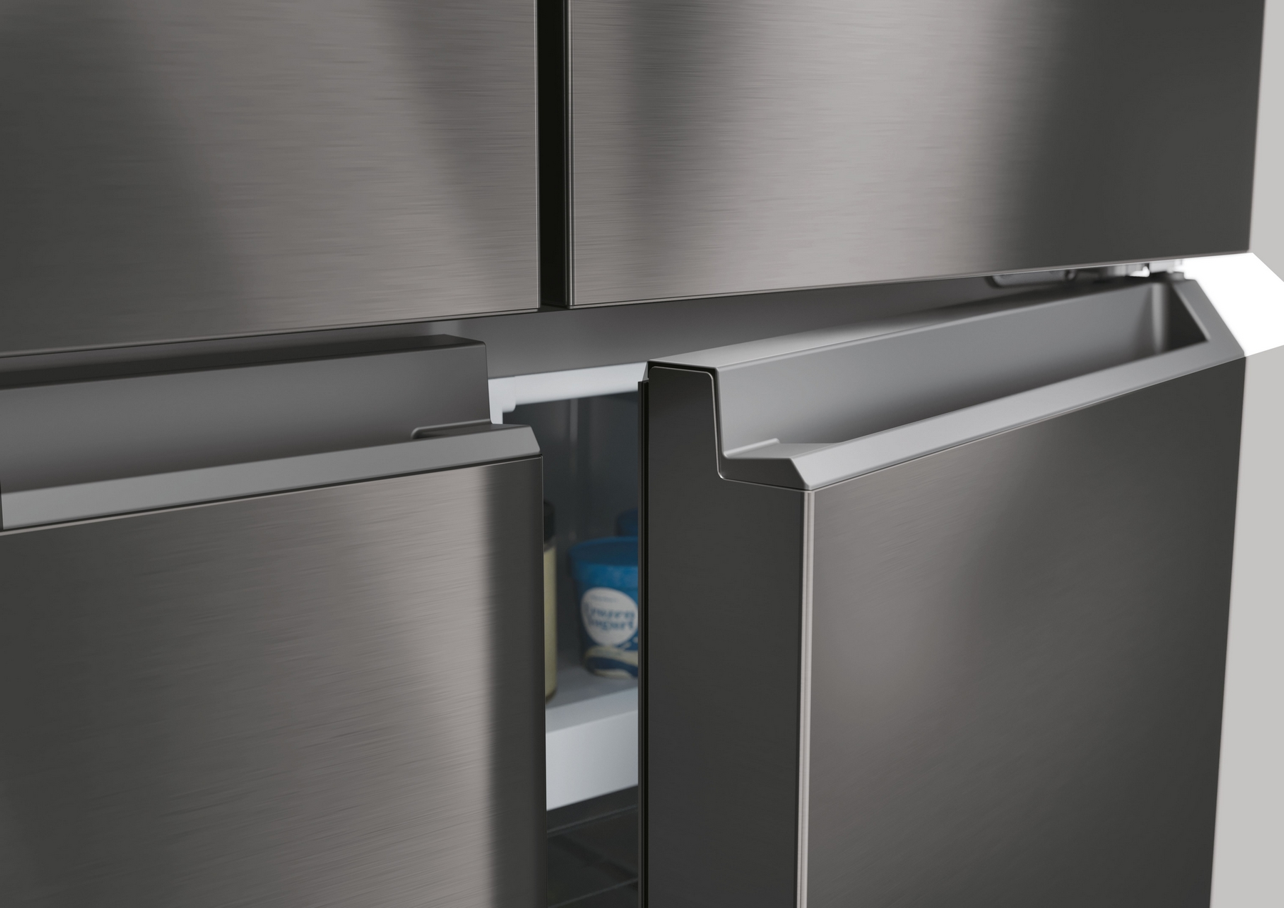 Primo piano di un frigorifero in acciaio inossidabile con la porta parzialmente aperta. All'interno, un ripiano contiene yogurt e altri articoli.