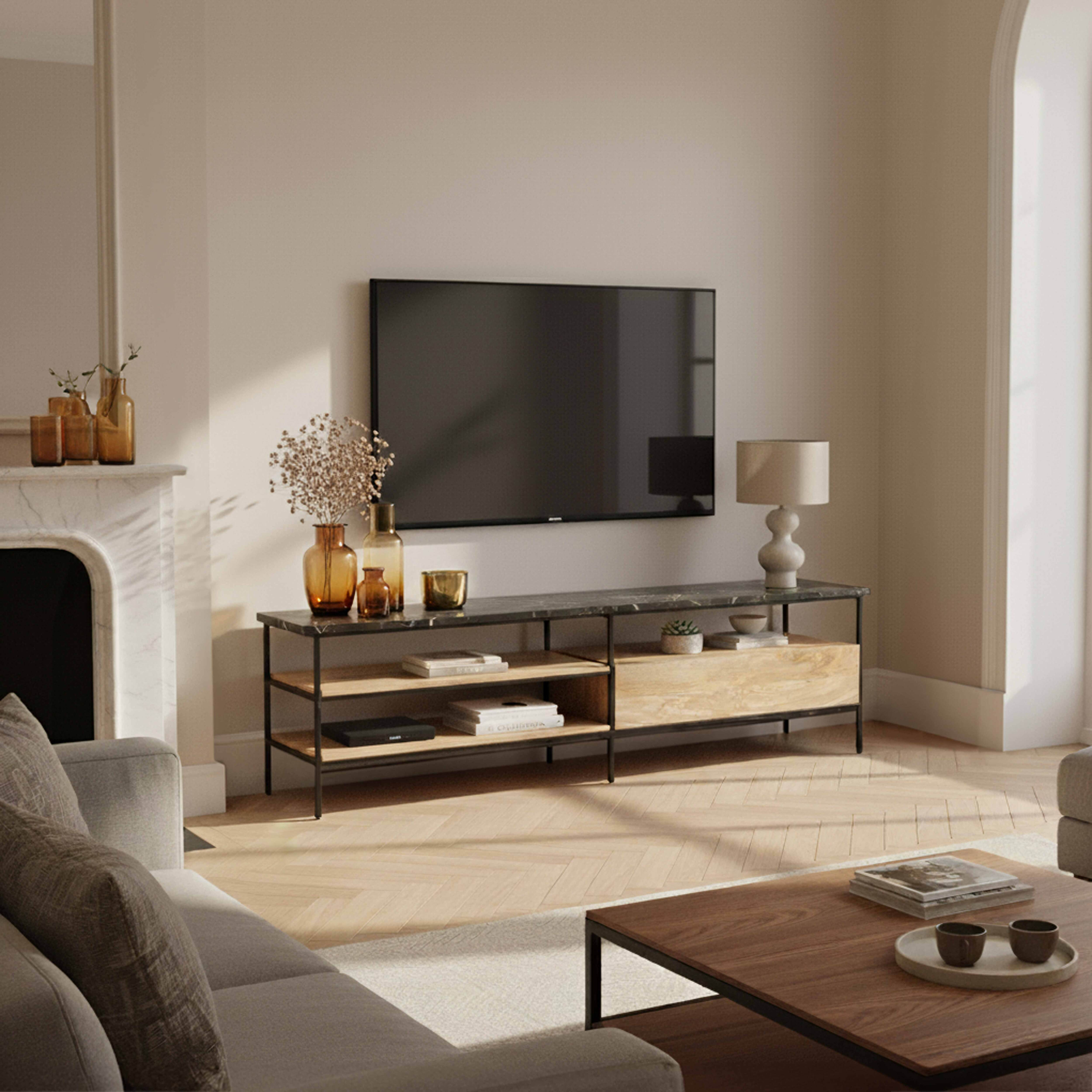 Wohnzimmer mit Fernseher über einem Tisch. Davor ein Sofa und ein Couchtisch. Sanfte Farben und eine warme Atmosphäre.