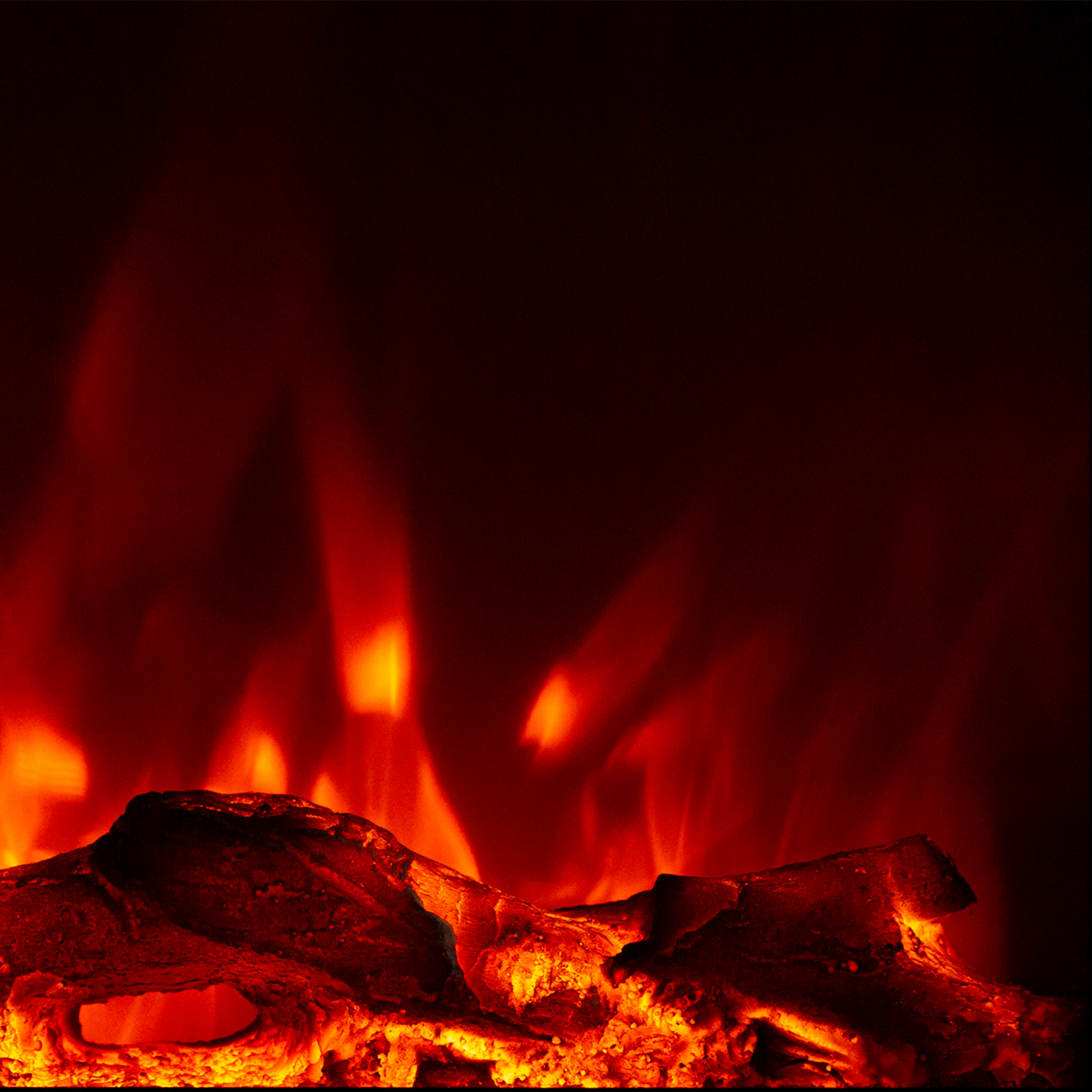 Nahaufnahme eines Kamins mit orangefarbenen Flammen über dunklen, glühenden Glut vor schwarzem Hintergrund.
