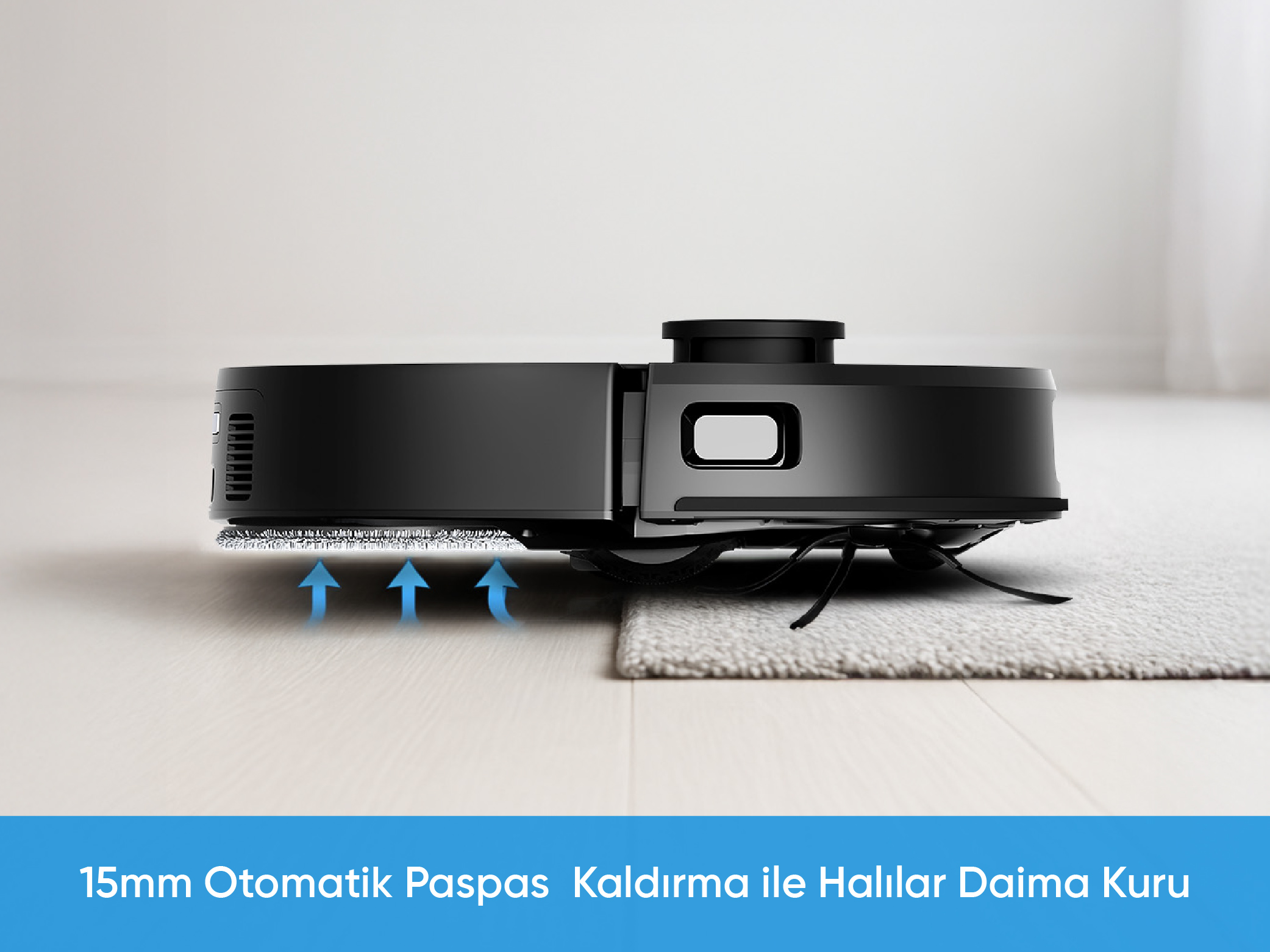 Zemin üzerinde siyah robot süpürge, kısmen halıda. Mavi oklar paspasın kalkışını gösterir.