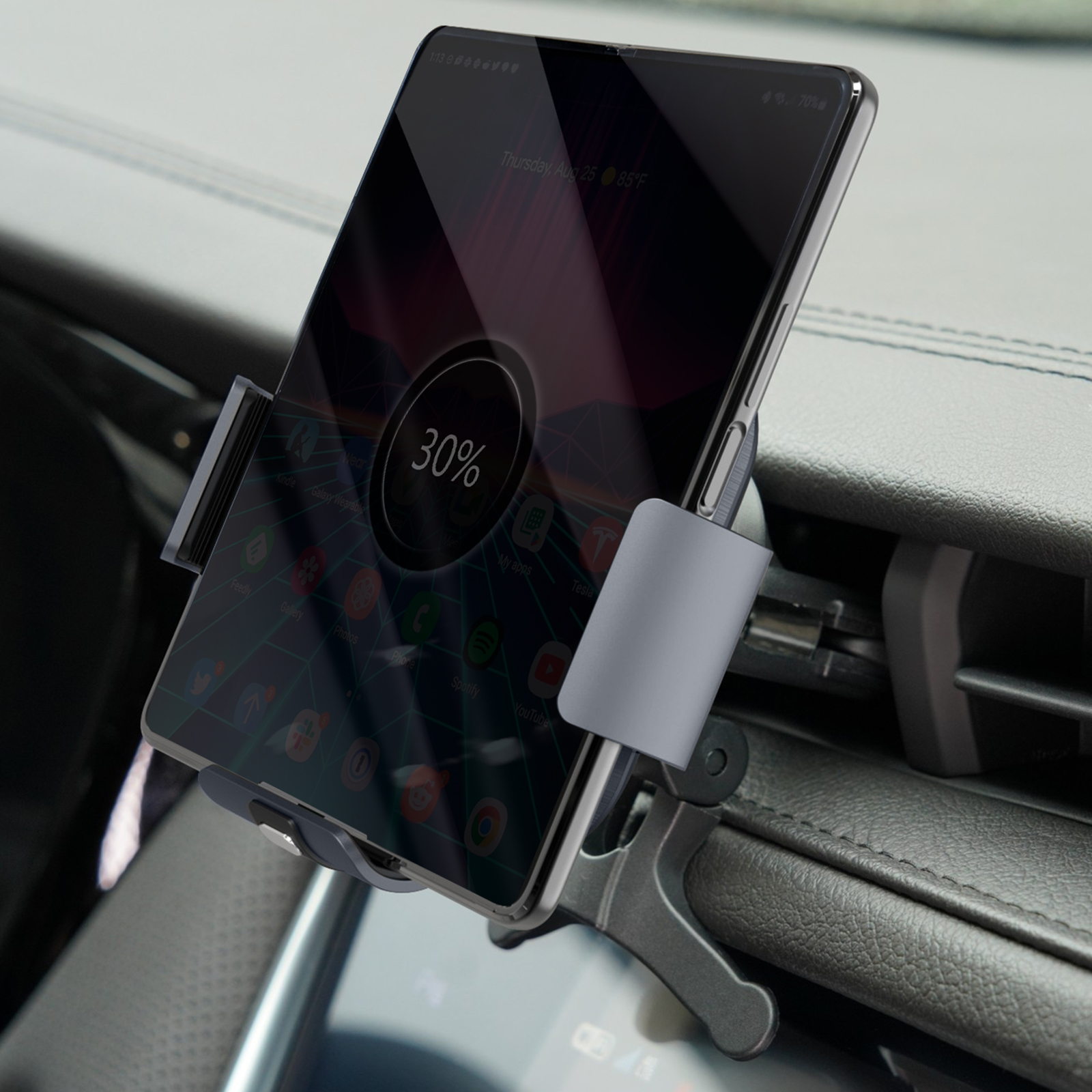 Un smartphone dans un support de voiture est en charge. L'écran affiche la date, l'heure et le pourcentage de batterie. Il est monté sur le tableau de bord.