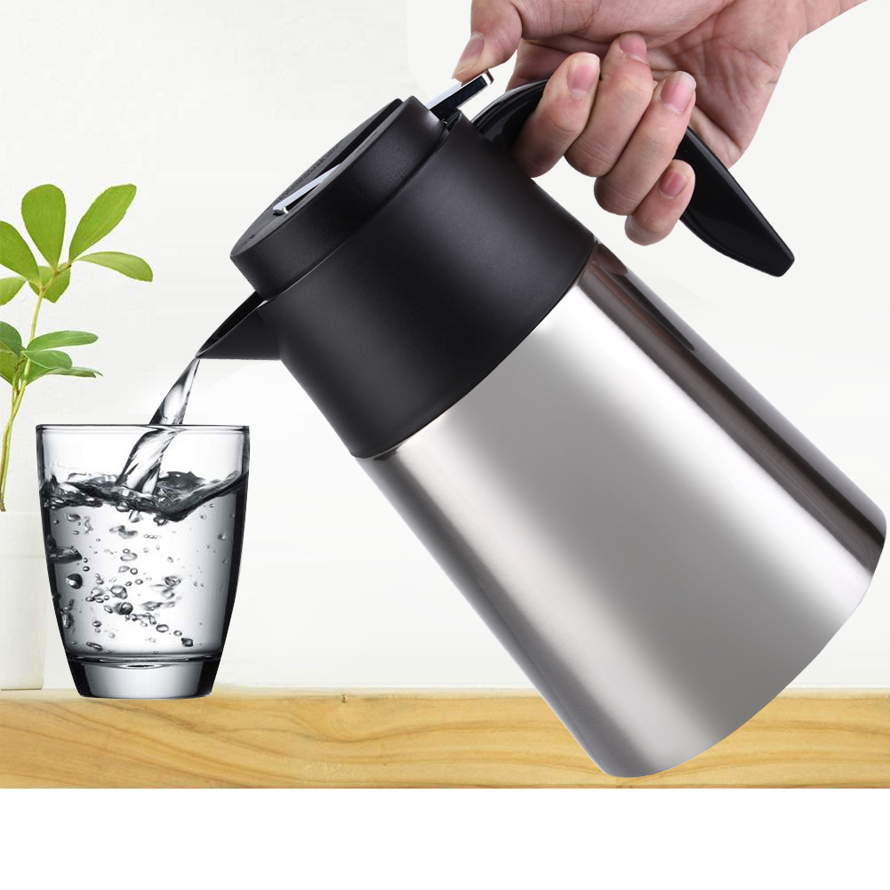 Eine Hand gießt Wasser aus einer silber-schwarzen Thermoskanne in ein Glas. Im Hintergrund befindet sich eine kleine Pflanze. Die Szene spielt auf einer Holzoberfläche.