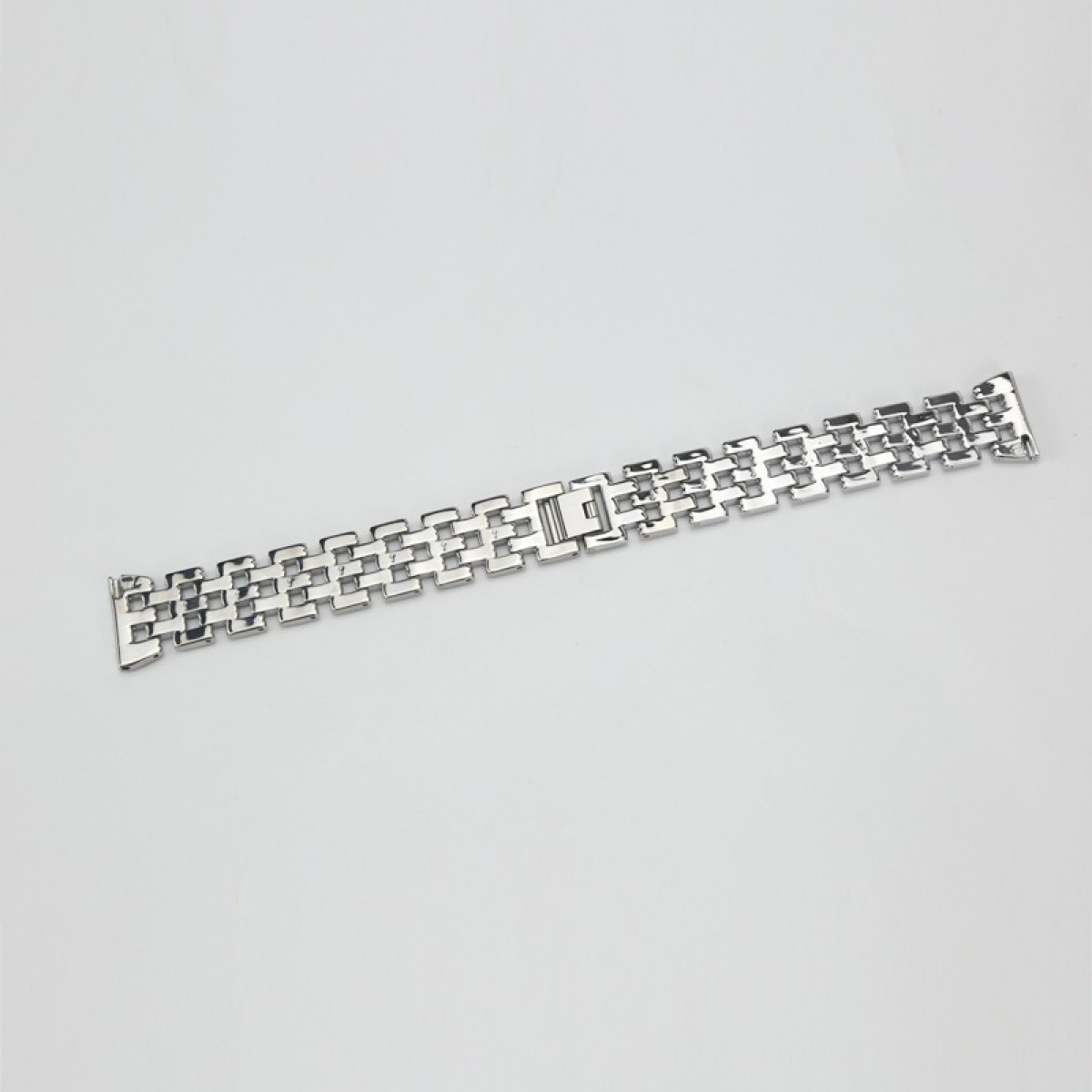 Ein silbernes Metall-Uhrenarmband liegt auf einer weißen Oberfläche. Es ist rechteckig mit sich wiederholenden Gliedern und einem Verschluss an der Seite.