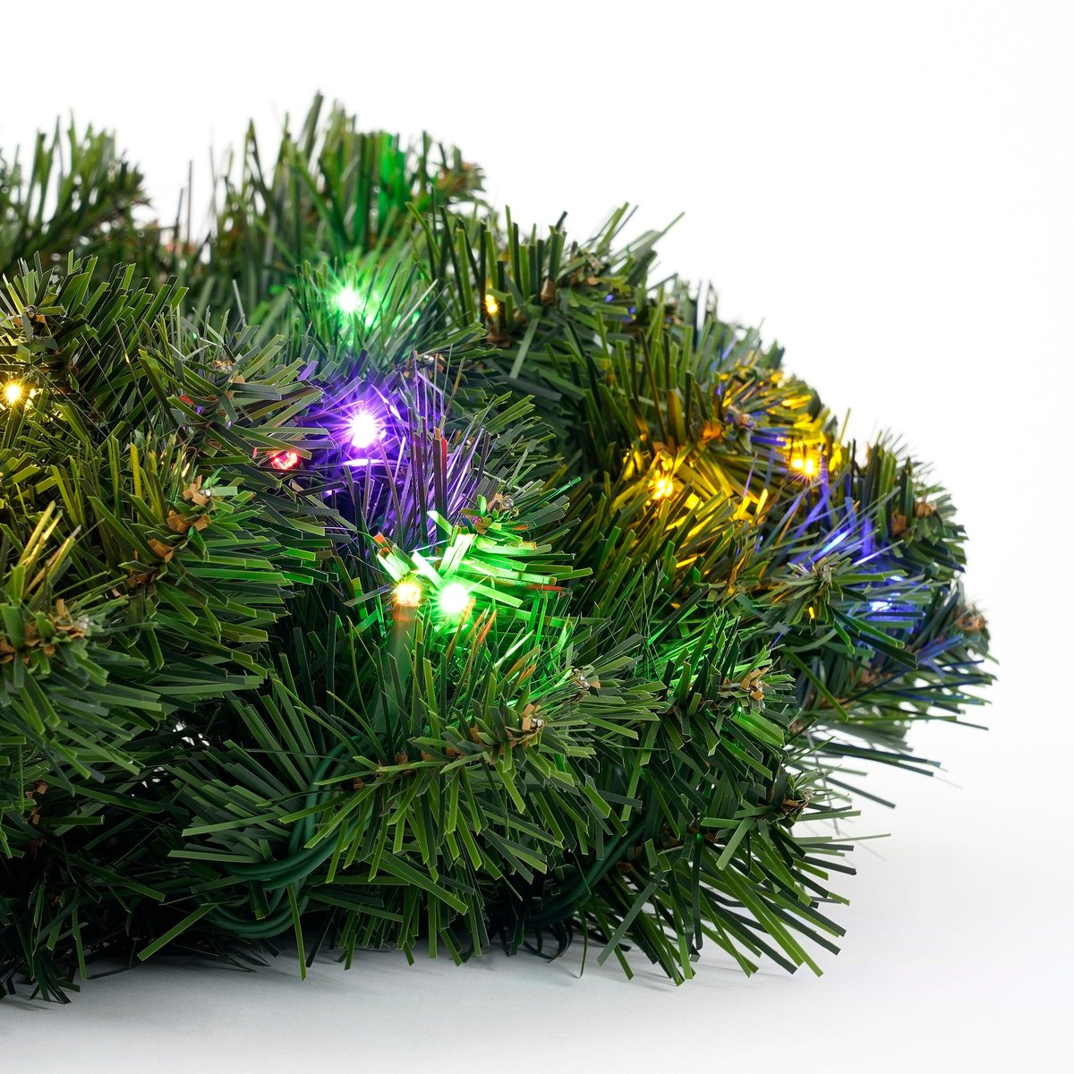 Une couronne de Noël verte avec des lumières colorées. Le fond est blanc.